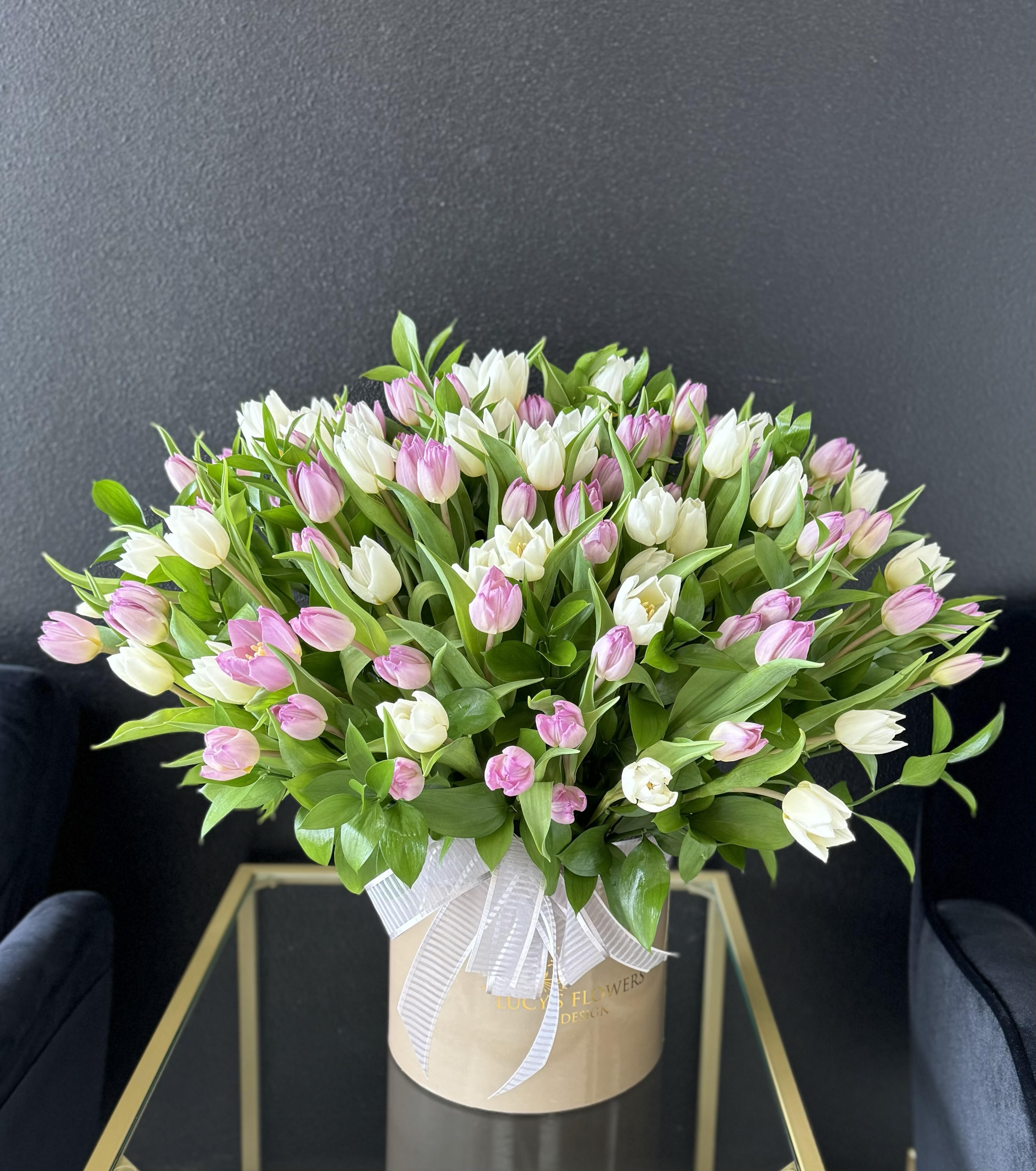 Pink and white tulips in a beige hatbox with a white ribbon