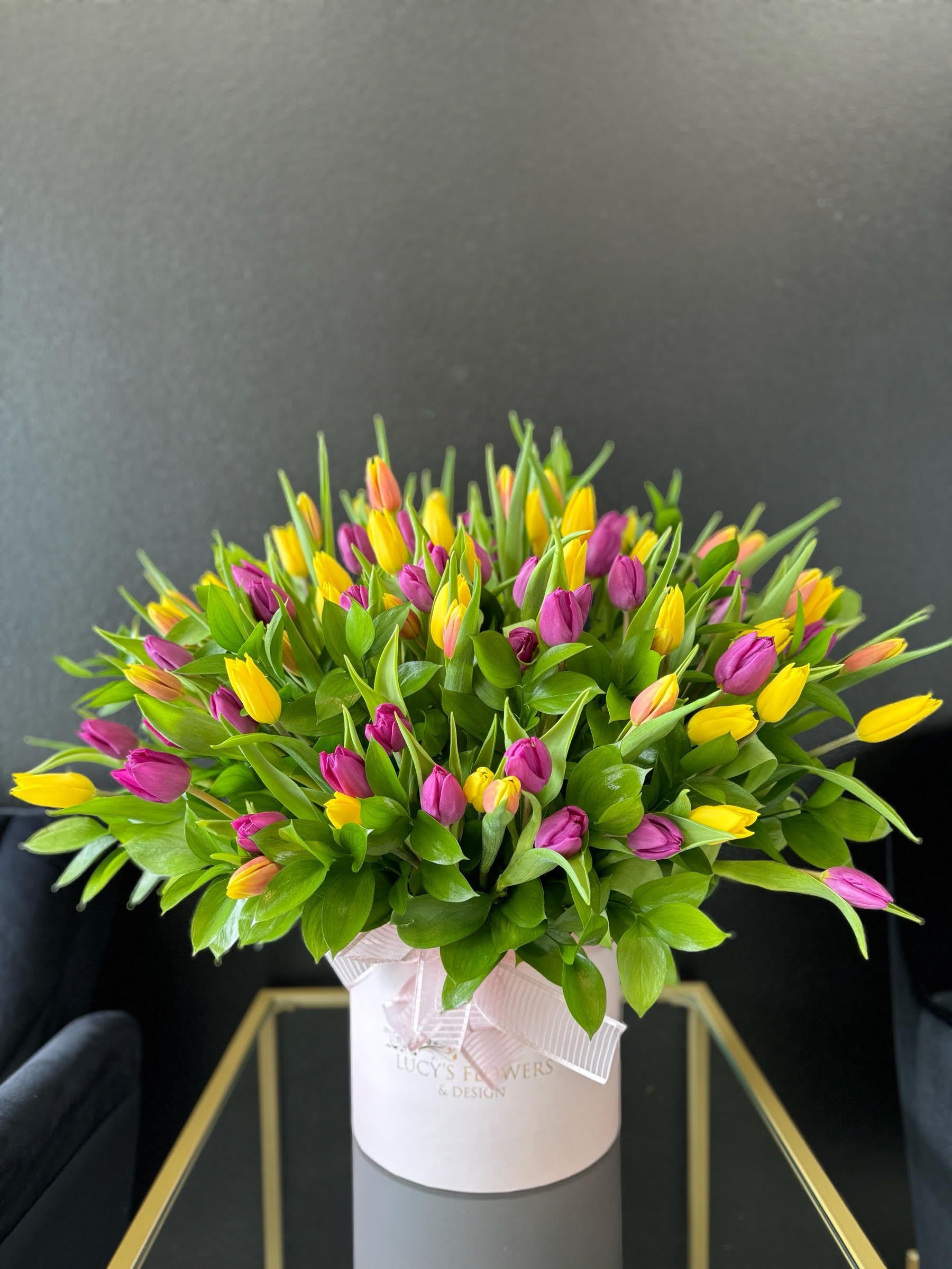  Spring Tulips - Flamboyant and colorful,  tulips – with their feathered, curled petals in bright, showy colors – create a dramatic bouquet. If you know someone who loves springtime flowers, and bulb blossoms in general, these pretty blooms will be a genuine treat.  Arrangement Includes: -Lucy's Medium Size Signature Box -Assorted Long Stem Tulips  -Custom Greeting Card -Care Instructions  Disclaimer: Photos shown on our website are the  Deluxe or Premium version of the arrangement.