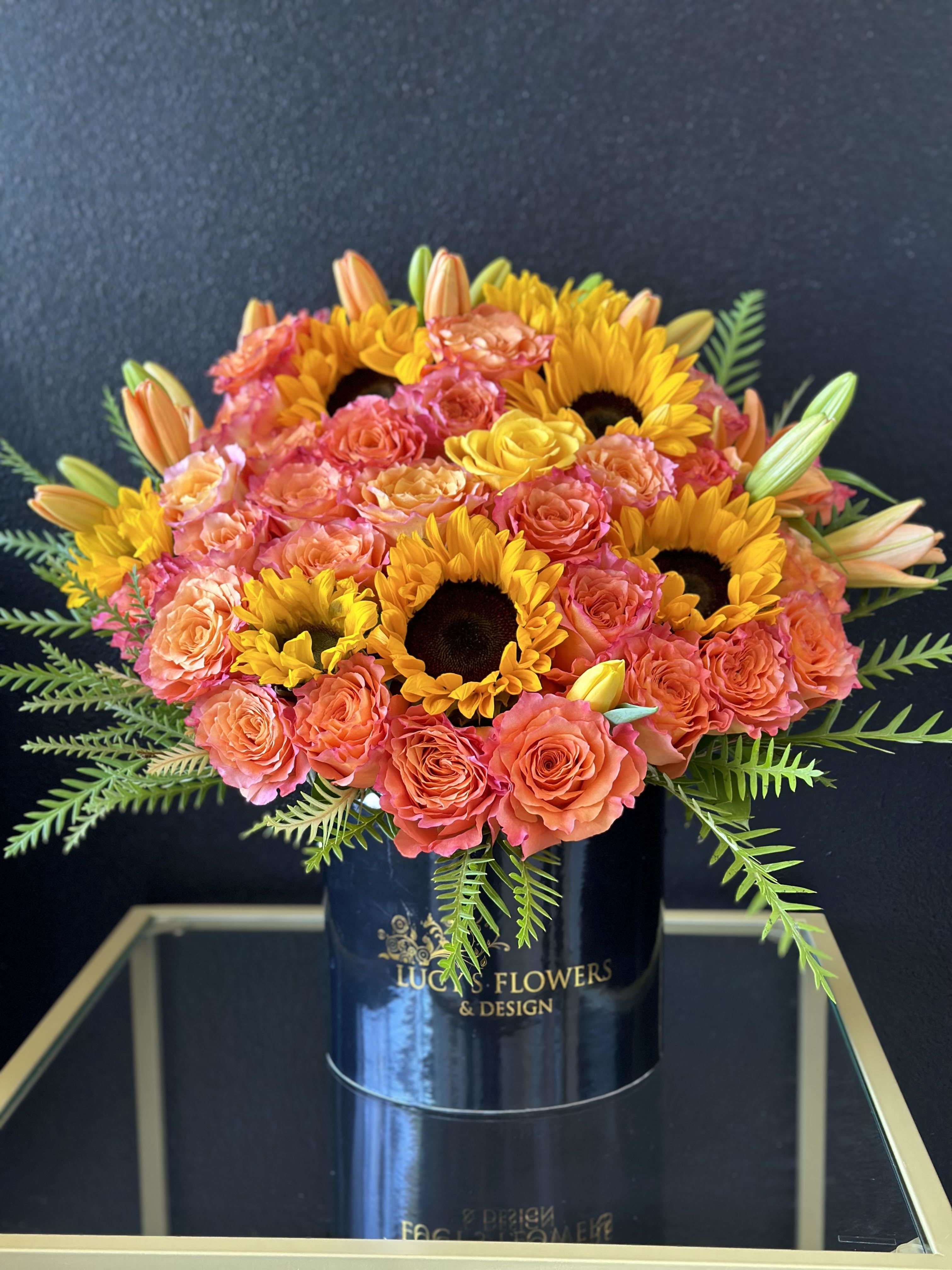 Bouquet of coral roses and yellow sunflowers in a black vase