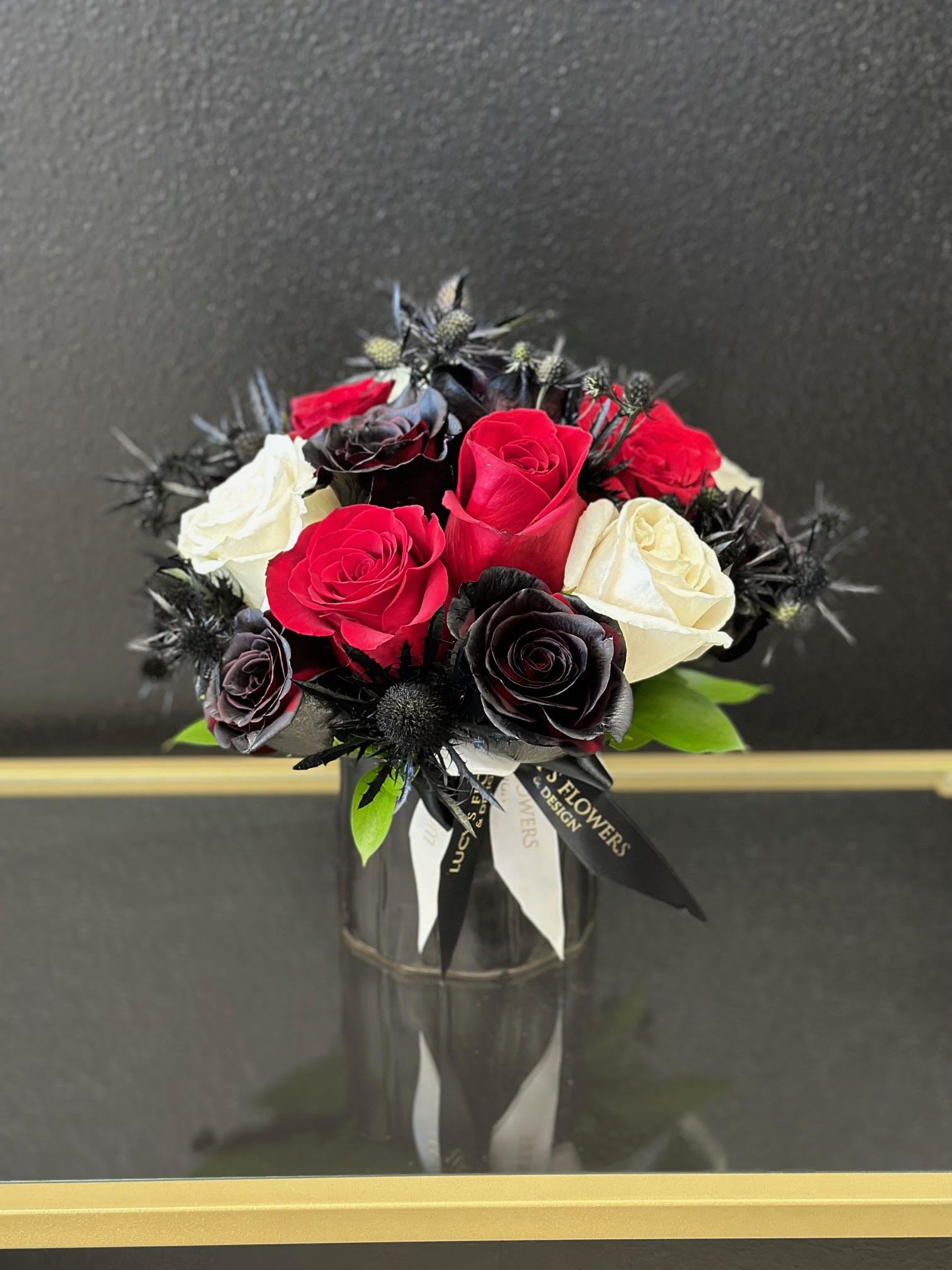 Bouquet of red, white, and black roses in a glass vase