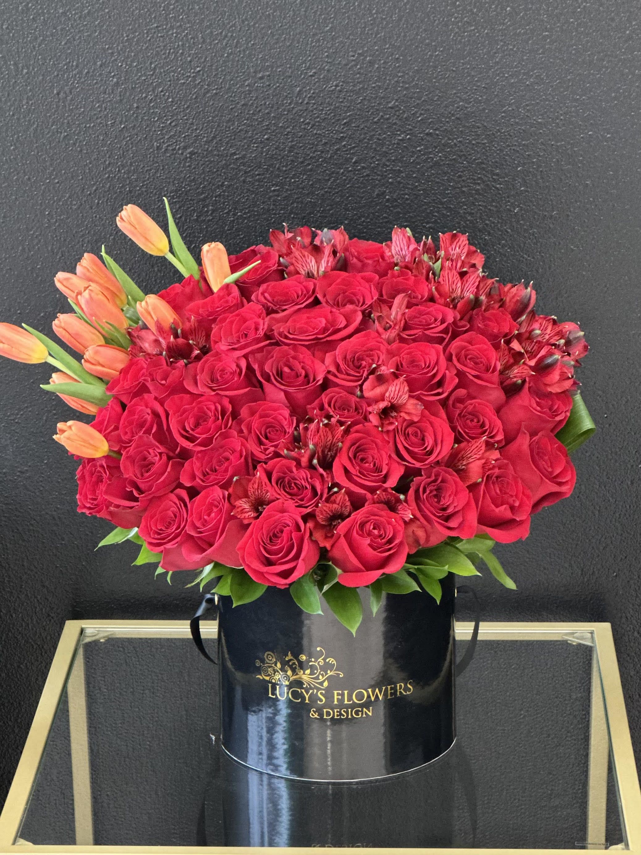 Red rose bouquet with orange tulips in a black hatbox