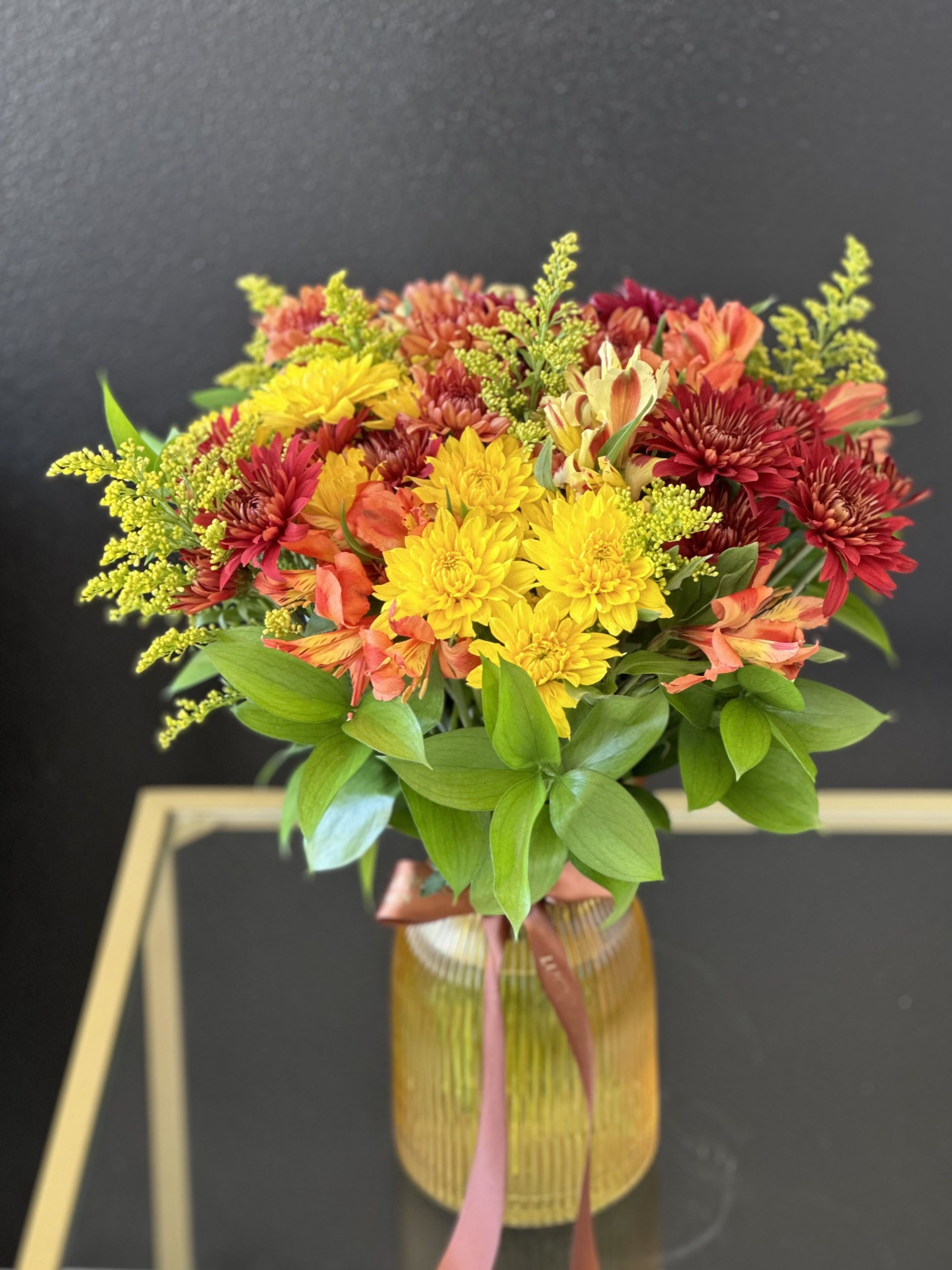 Bouquet of yellow, red, and orange flowers in a ribbed glass vase