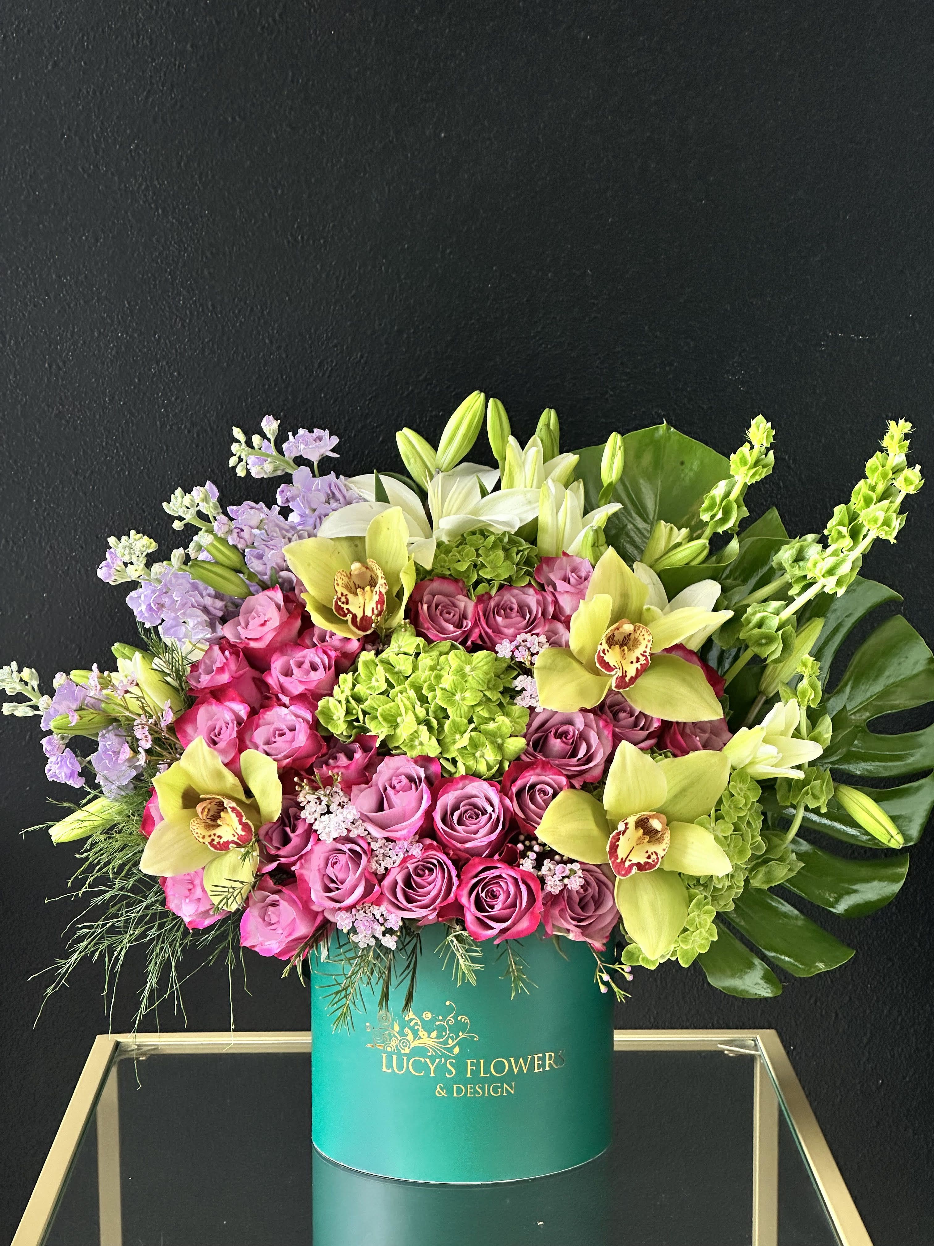 Pink roses and yellow orchids in a teal hatbox