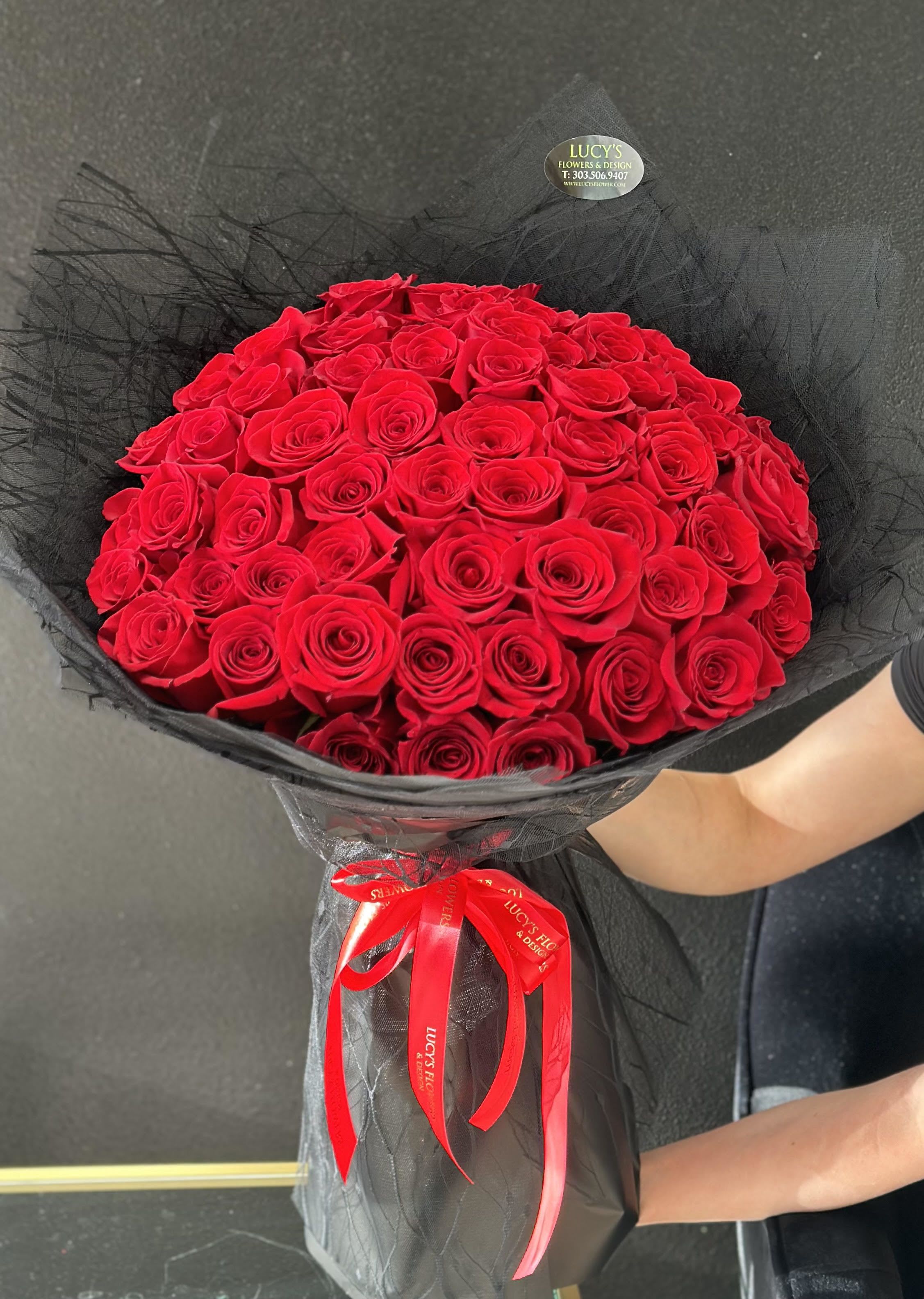 Large bouquet of red roses wrapped in black mesh with a red ribbon
