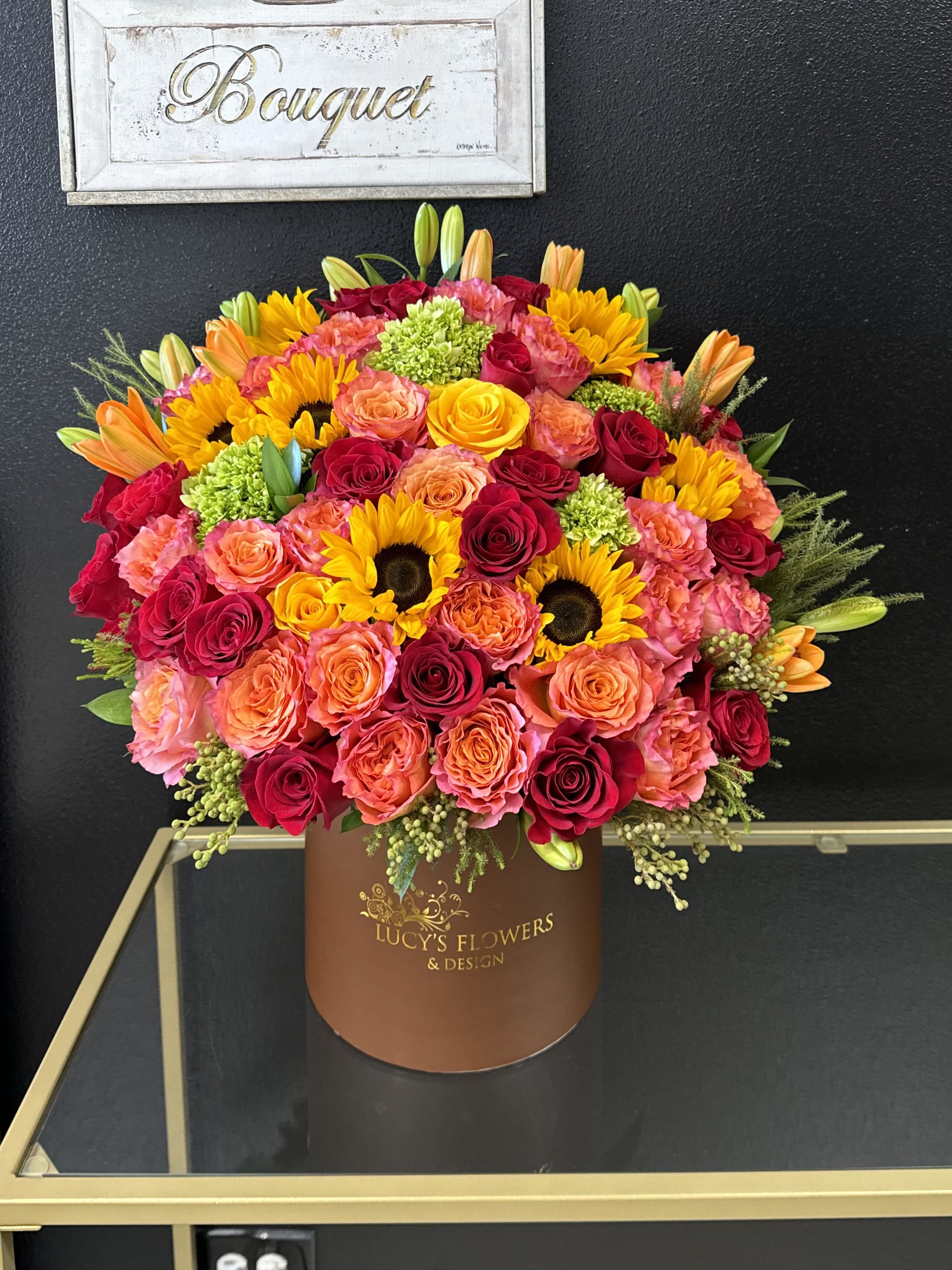 Large bouquet of roses, sunflowers, and lilies in a brown box