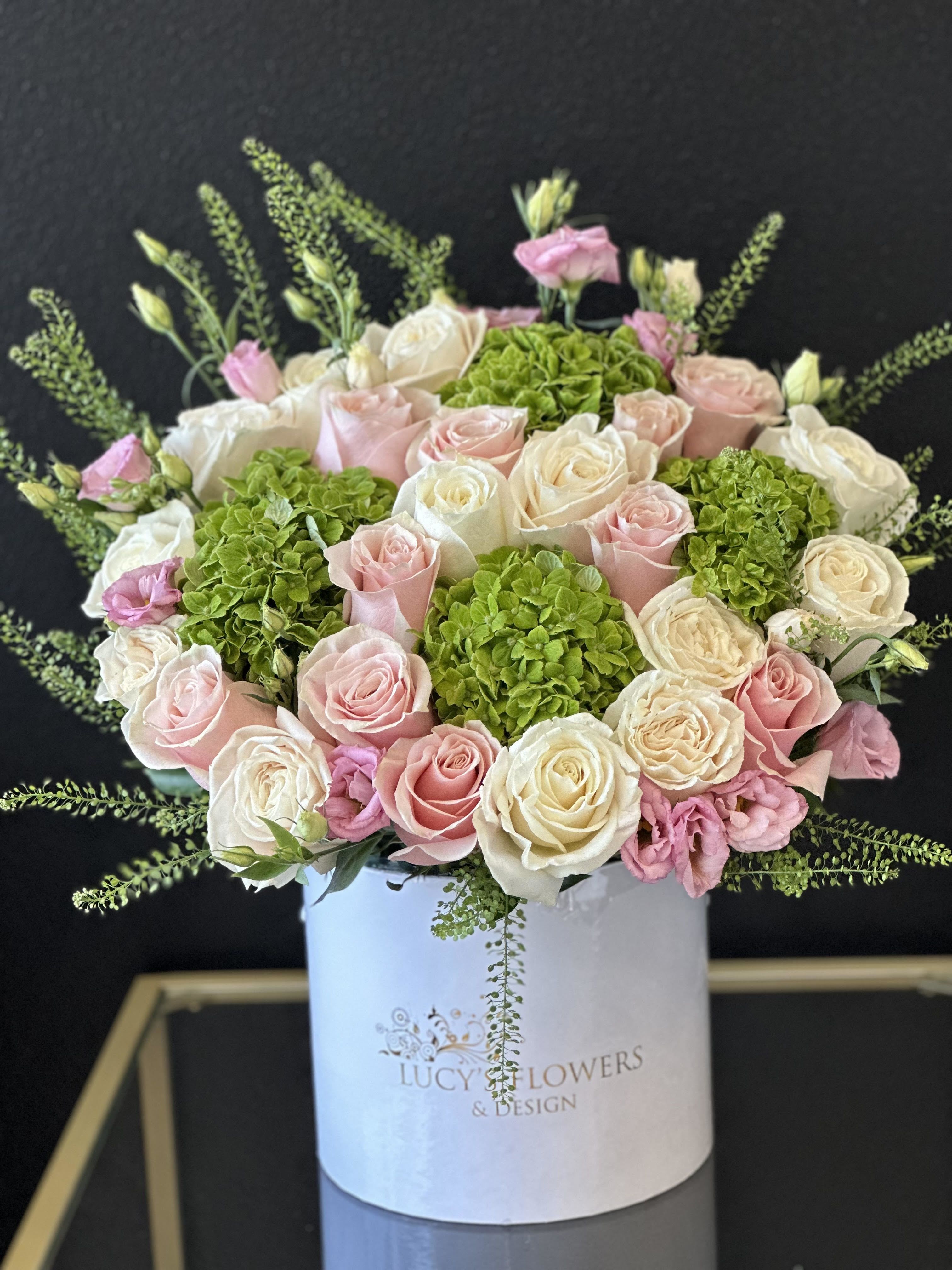 Pink and white roses with green hydrangeas in a white hatbox