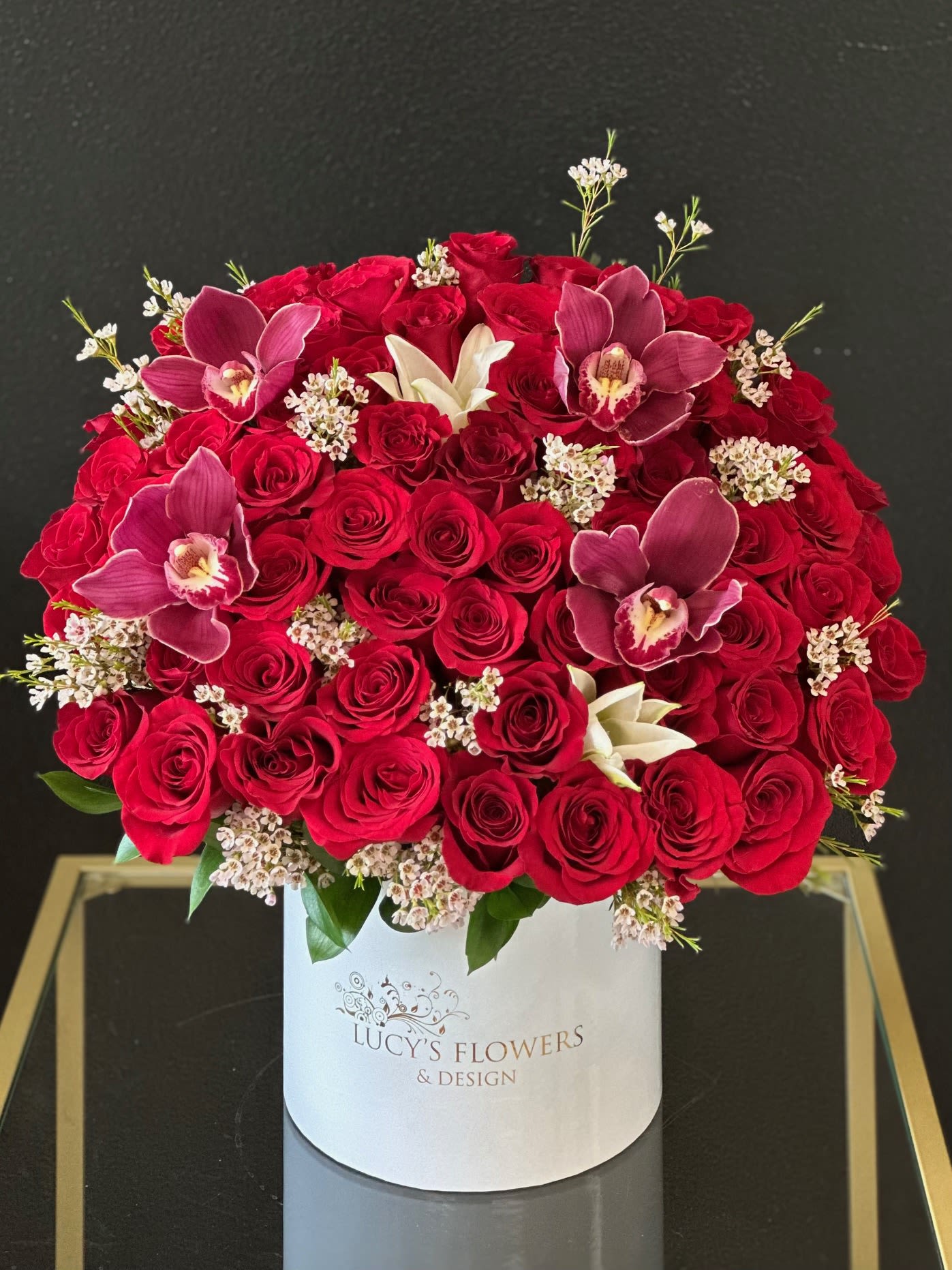 Red rose arrangement with orchids in a white hat box