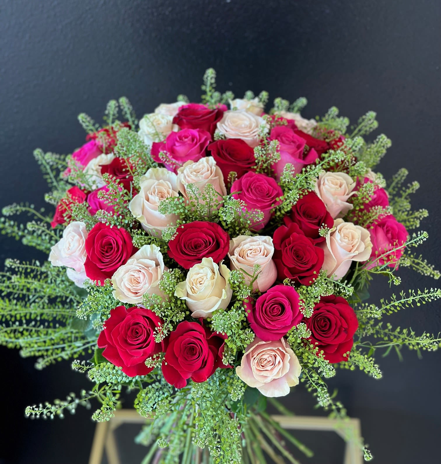 Bouquet of red, pink, and blush roses with airy greenery