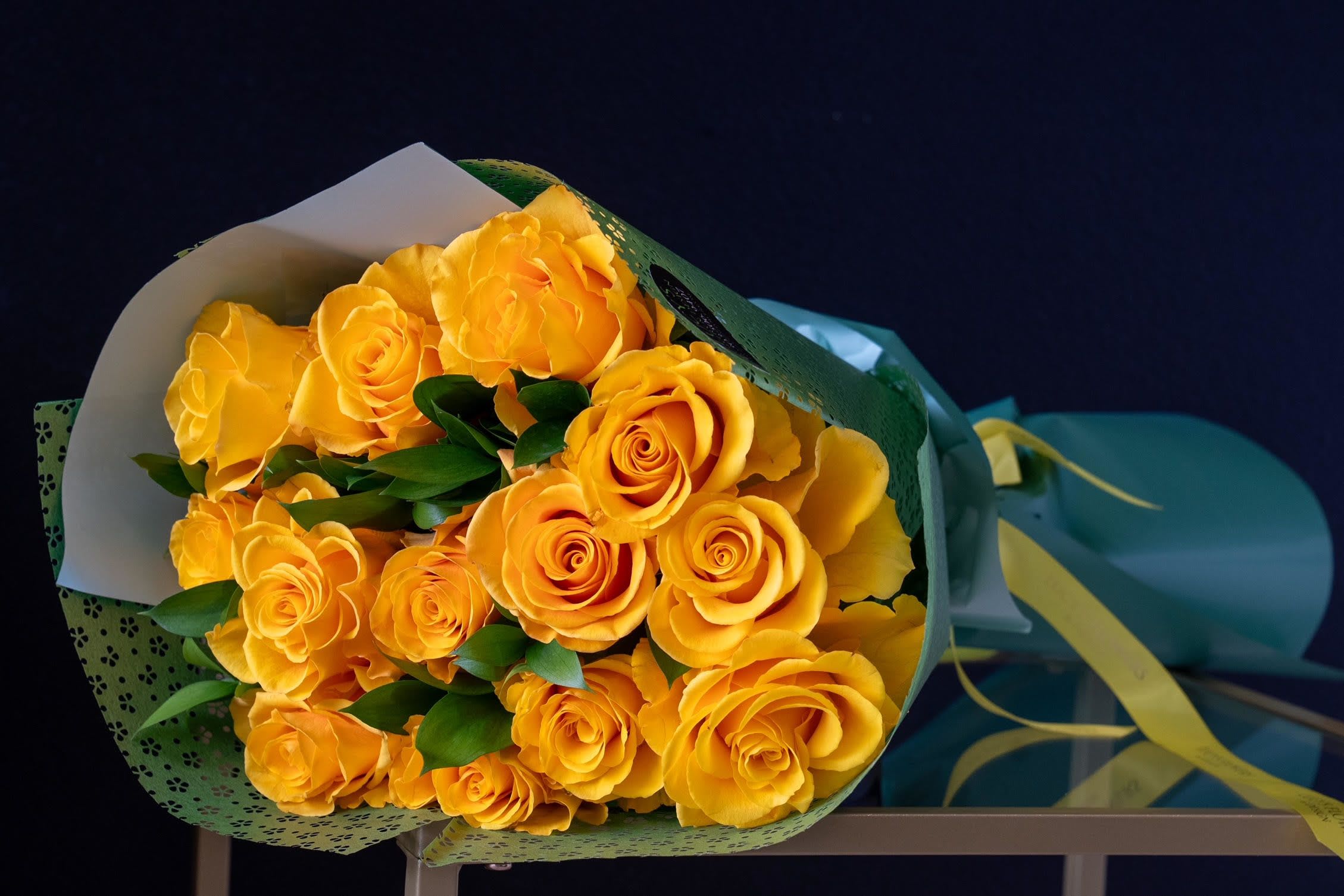 Dozen Long Stemmed Yellow Rose Bouquet - Long Stem Yellow Rose Bouquet is a radiant expression of joy, friendship, and warmth. Featuring long-stemmed yellow roses, each bloom is carefully selected for its bright, cheerful color and graceful form. The vibrant yellow petals symbolize happiness, new beginnings, and positivity, making this bouquet the perfect choice to celebrate life’s special moments. Whether it’s to express appreciation, bring sunshine to someone’s day, or mark an occasion, this bouquet is sure to deliver a burst of brightness and happiness.  Arrangement Includes: -Fresh Cut Long Stemmed Yellow Roses (12 count, 60"-70") -Assorted Greenery -Custom Paper Wrapping -Custom Greeting Card -Care Instructions