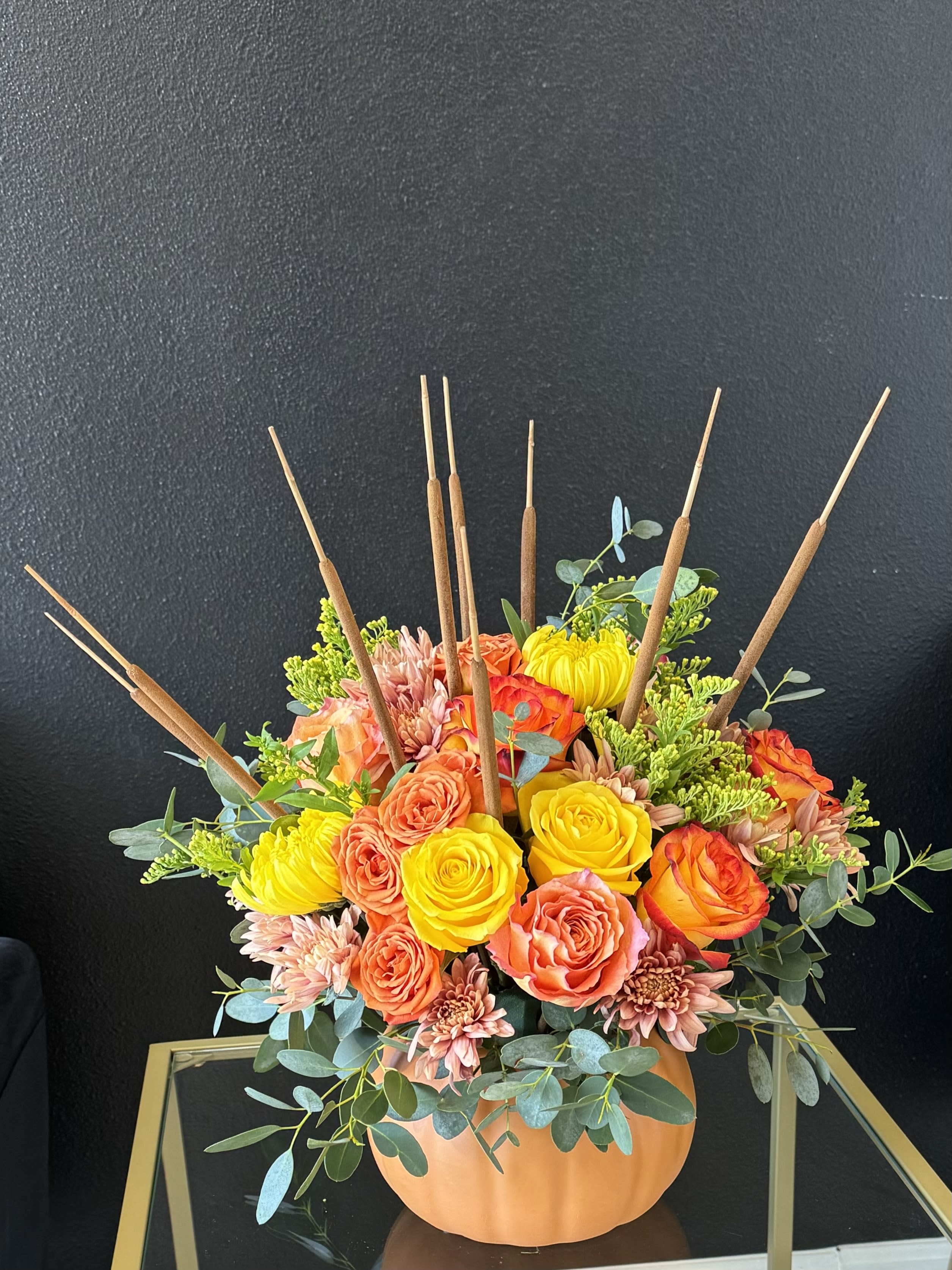 Orange and yellow floral arrangement in a pumpkin-shaped container