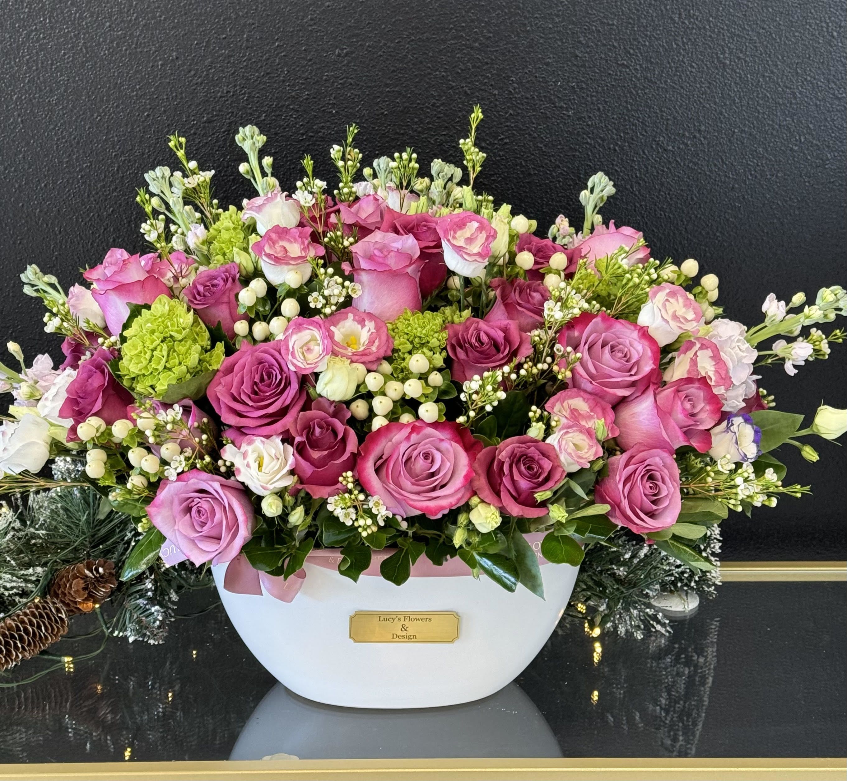 Pink and lavender rose arrangement in a white container
