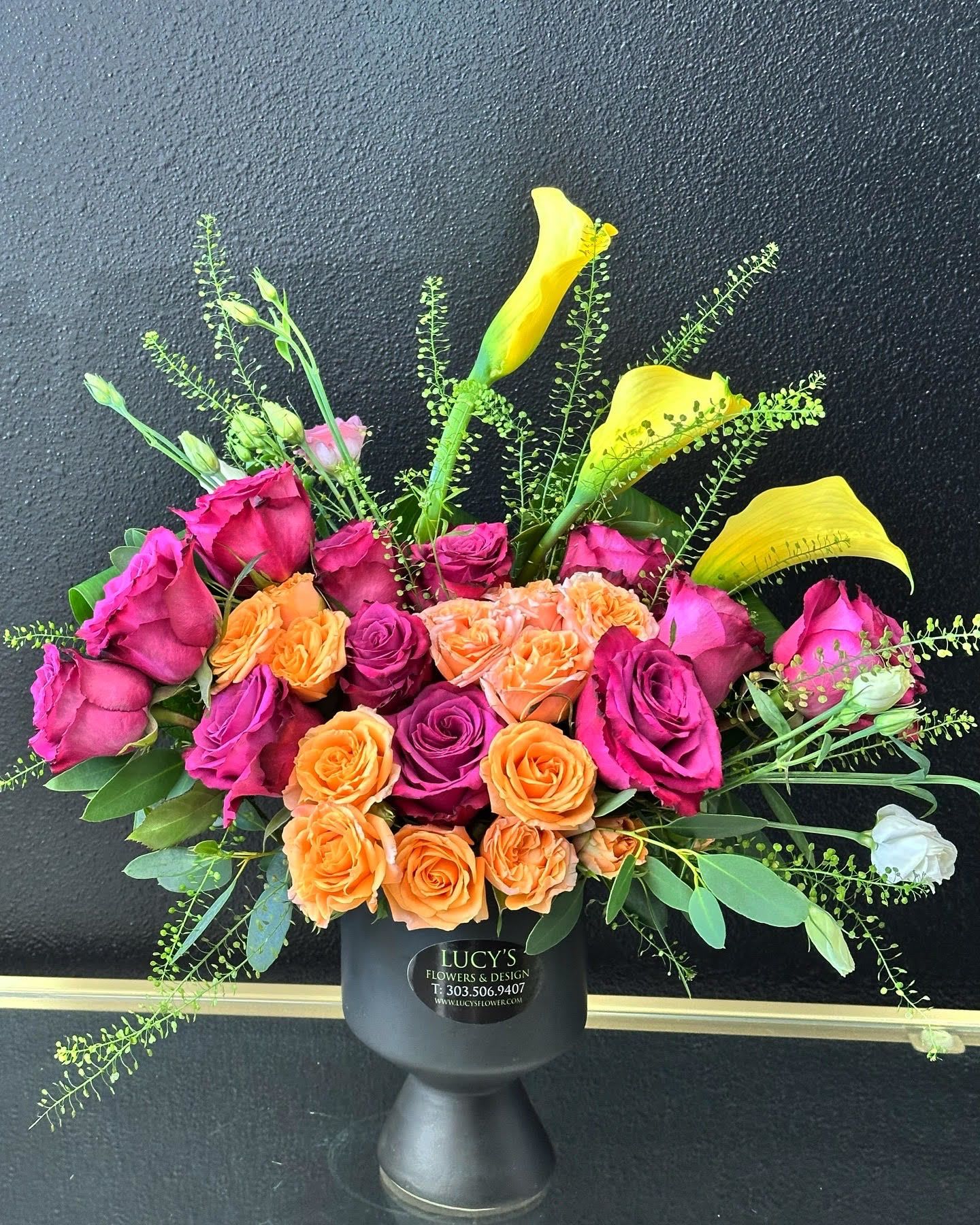 Exquisitee - This modern display of purple and orange roses and kala lilies with a touch of white lisianthus is a delicate and unique way to send flowers for a birthday, thank you, congratulations or just because. 