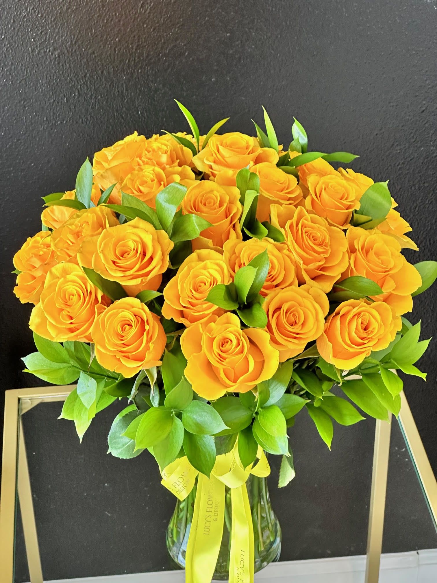 Bouquet of yellow roses with green foliage in a glass vase