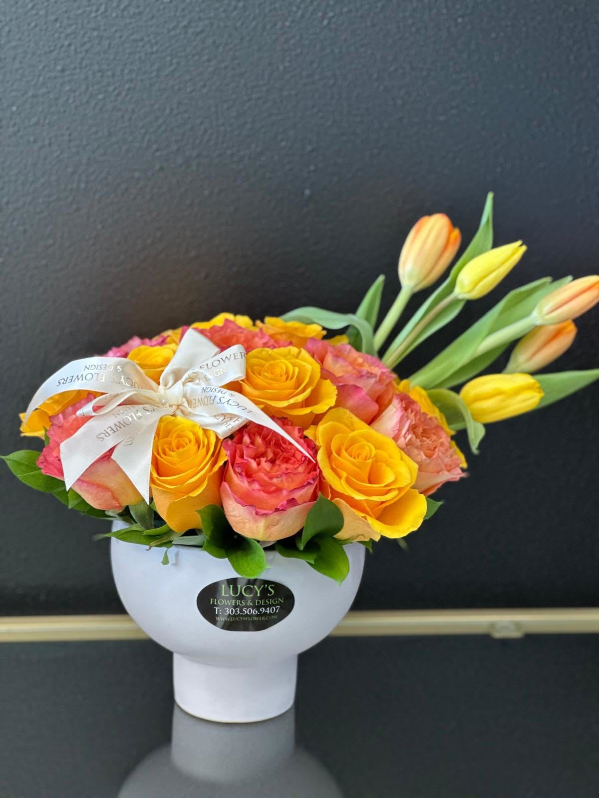 The Sound of Joy  - Send an explosion of color with this modern rose arrangement perfect for celebrations or showing your appreciation. A great alternative to the classic red rose, send a unique arrangement of multicolored bright roses.  Arrangement Includes: -Fresh Cut Orange, Yellow Roses, &amp; Tulips -White Porcelain Vase -Custom Greeting Card -Care Instructions
