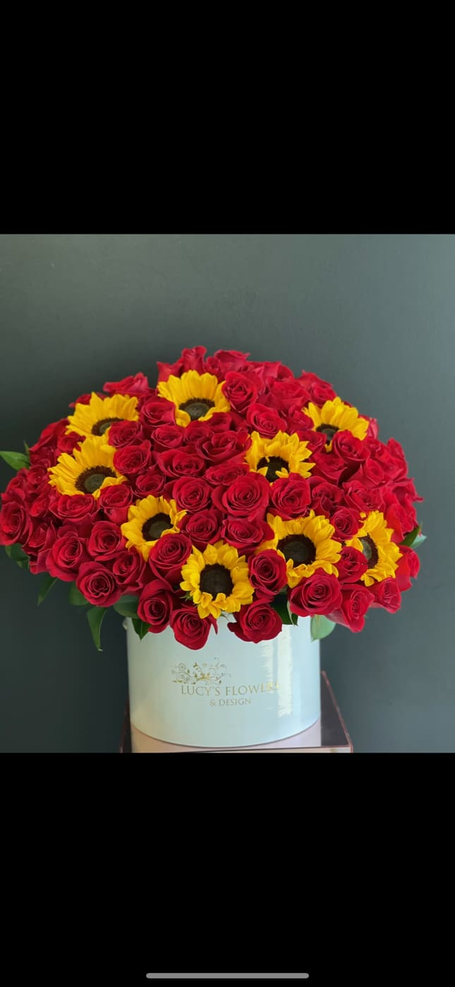 Red roses and yellow sunflowers in a white hat box