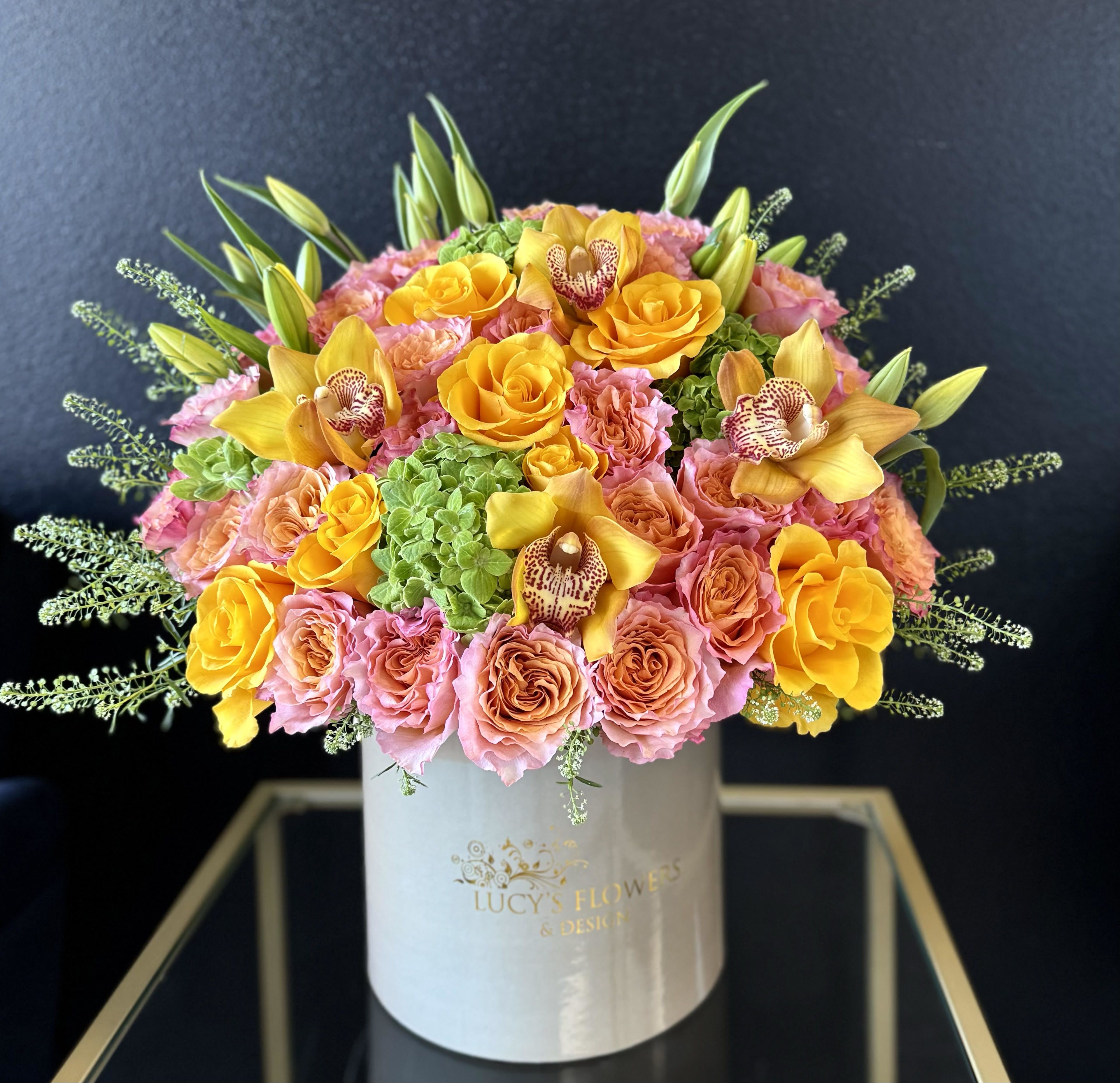 Pink and yellow rose bouquet in a white hat box with orchids