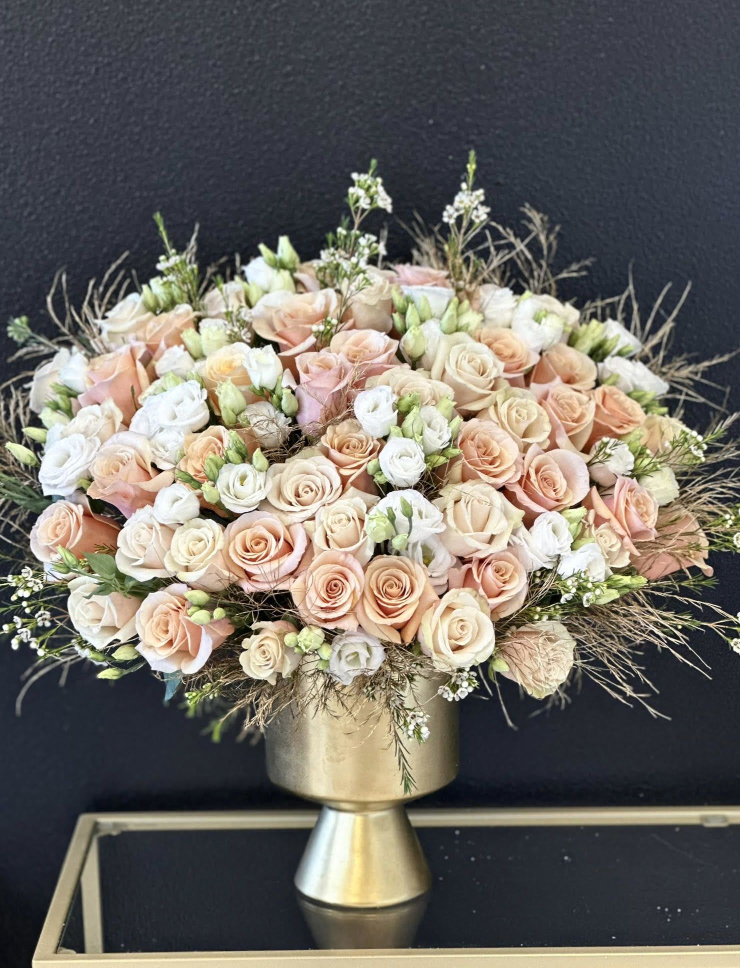Peach and white rose bouquet in a gold pedestal vase