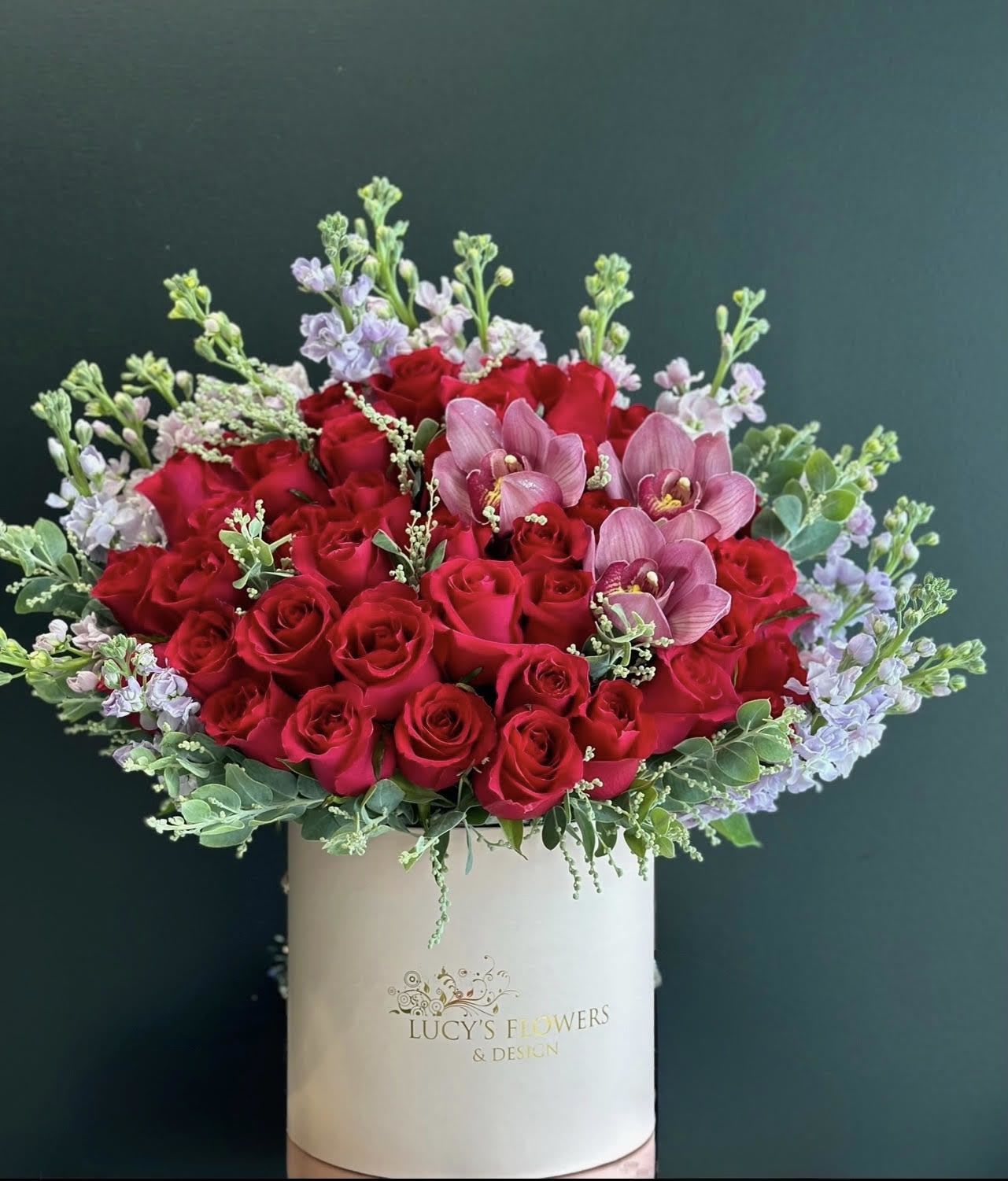 Red roses and pink orchids in a white hat box