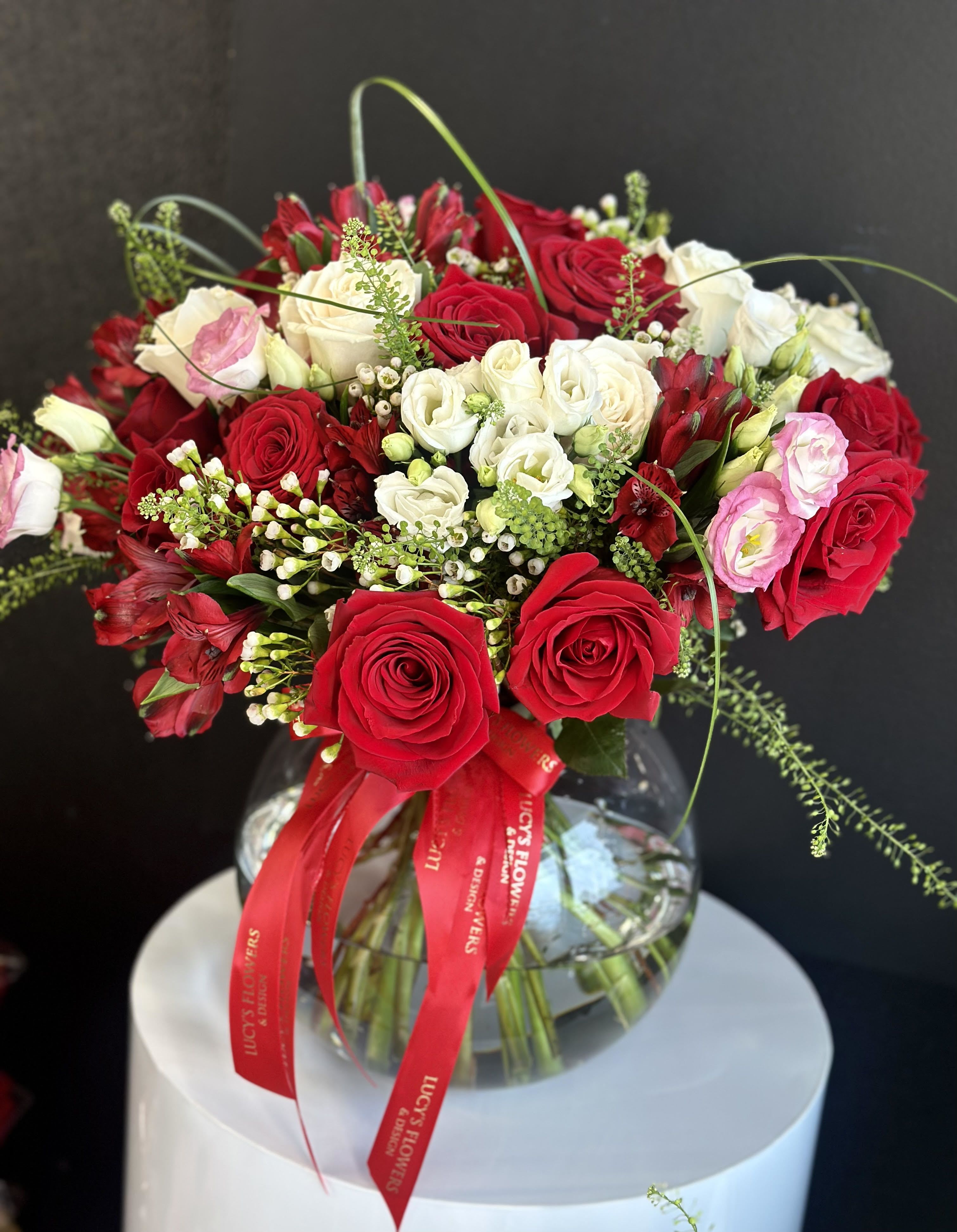 Bouquet of red and white roses in a glass vase with a red ribbon