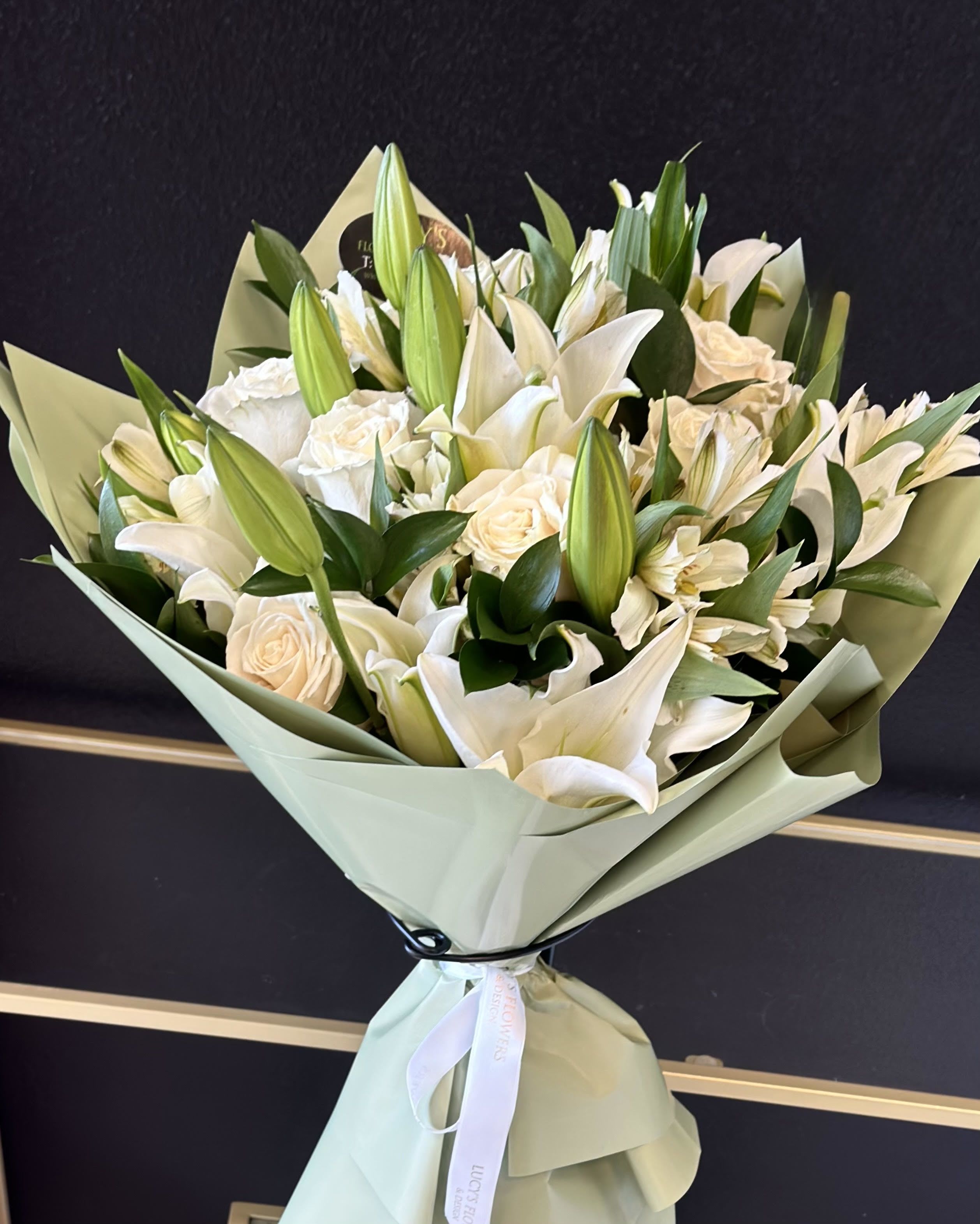 White lily and rose bouquet wrapped in pale green paper