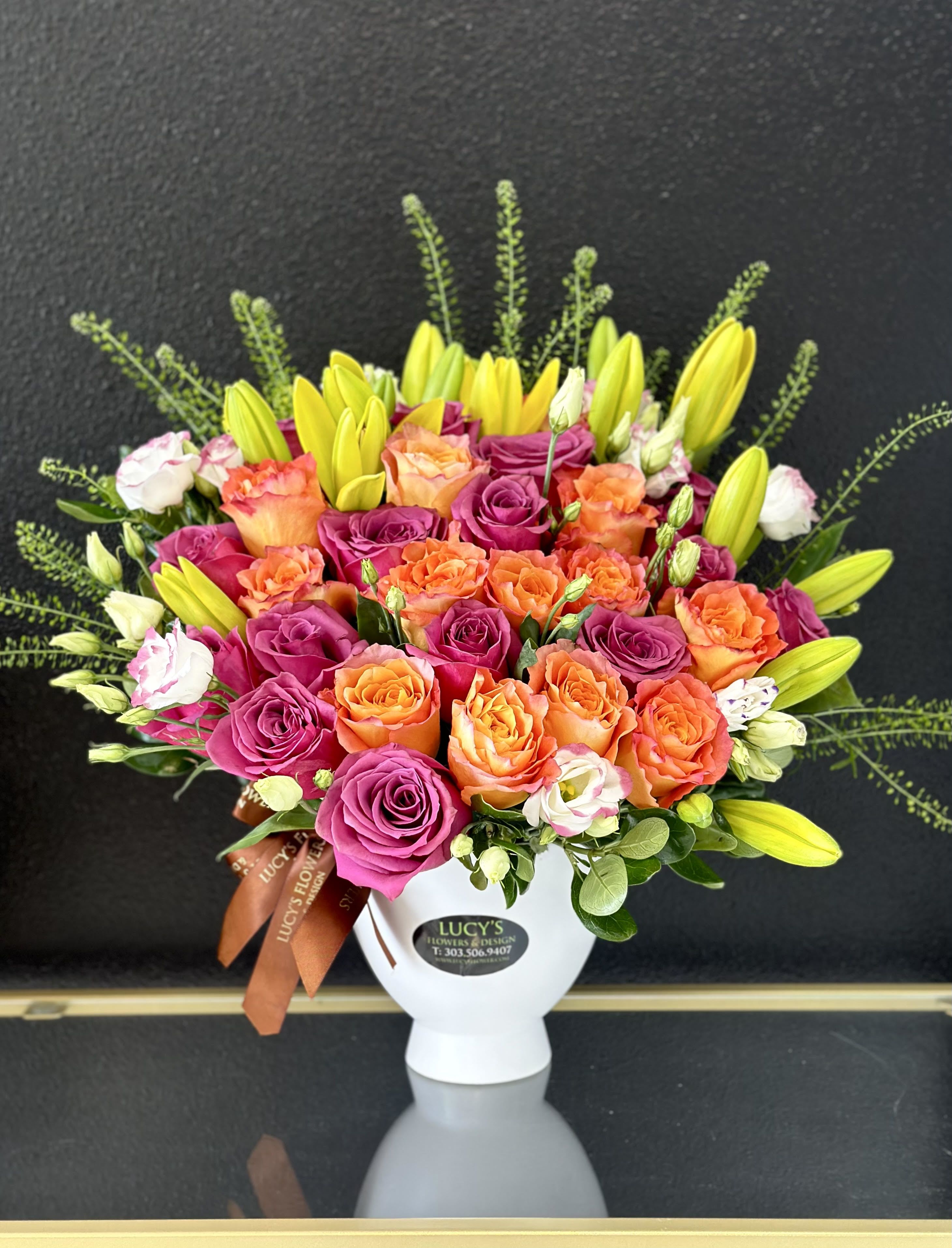 Bouquet of pink and orange roses with yellow lilies in a white vase
