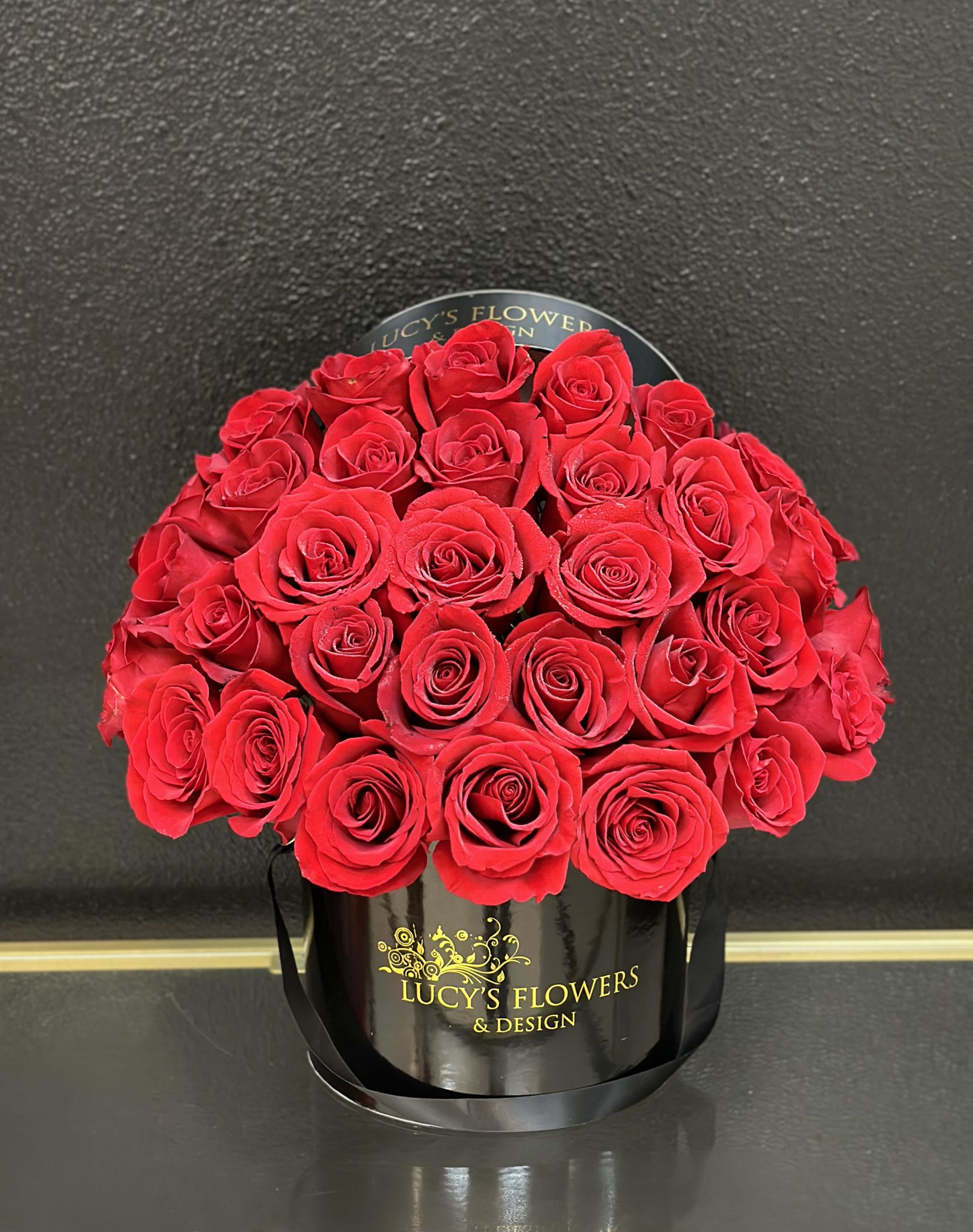Red roses arranged in a black round box
