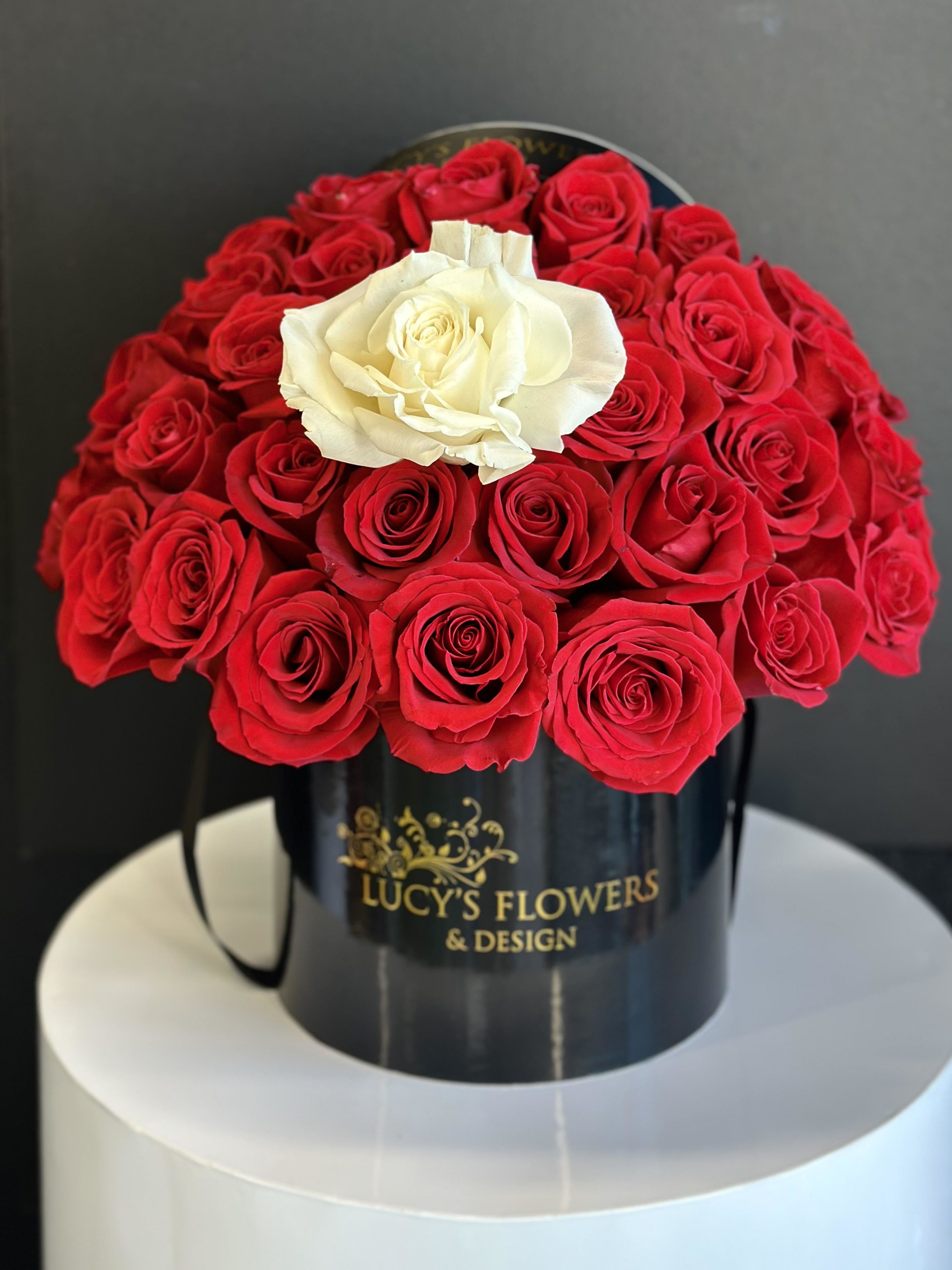 Red and white roses arranged in a black hatbox