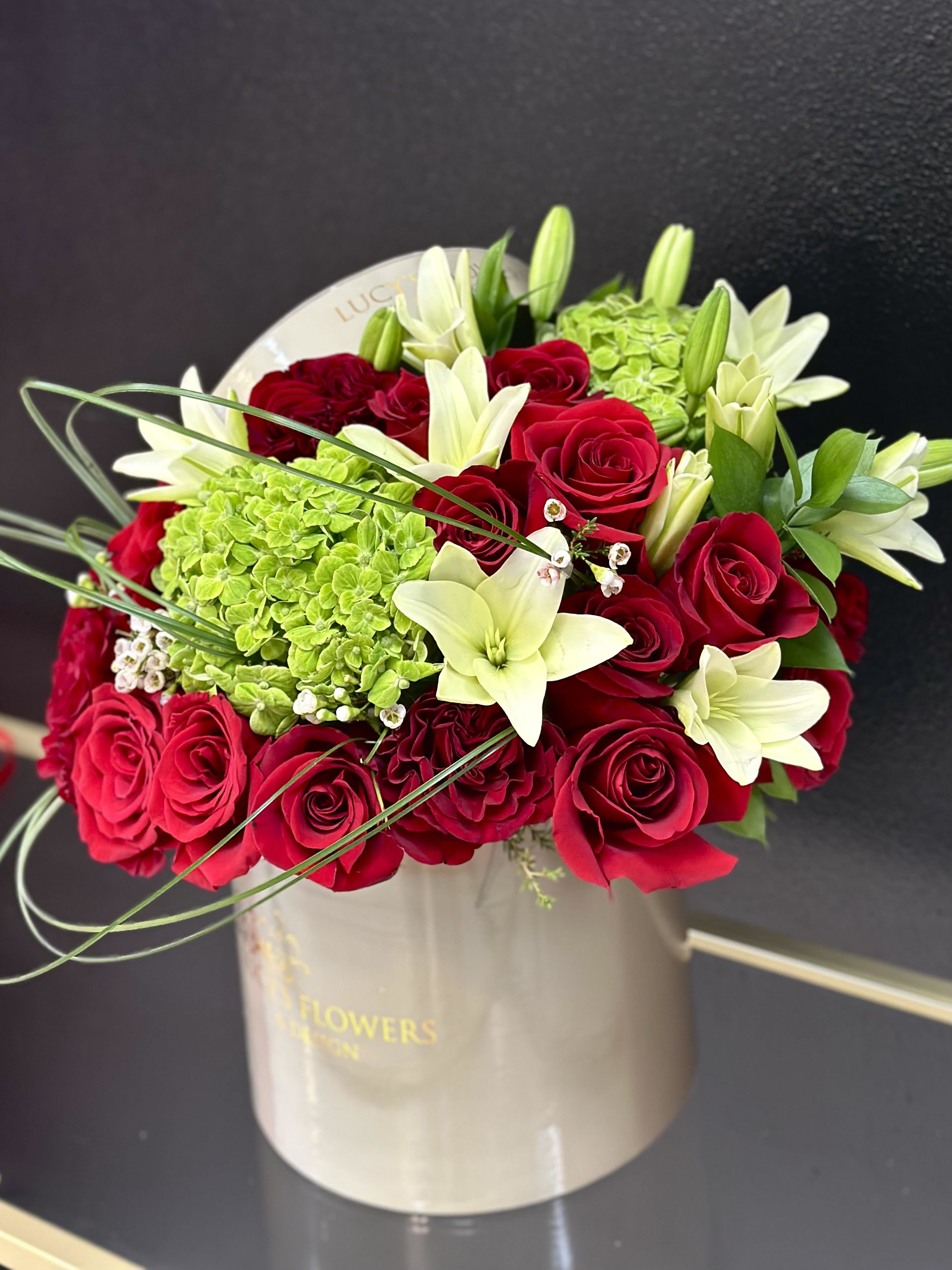 Red roses and white lilies in a beige hatbox