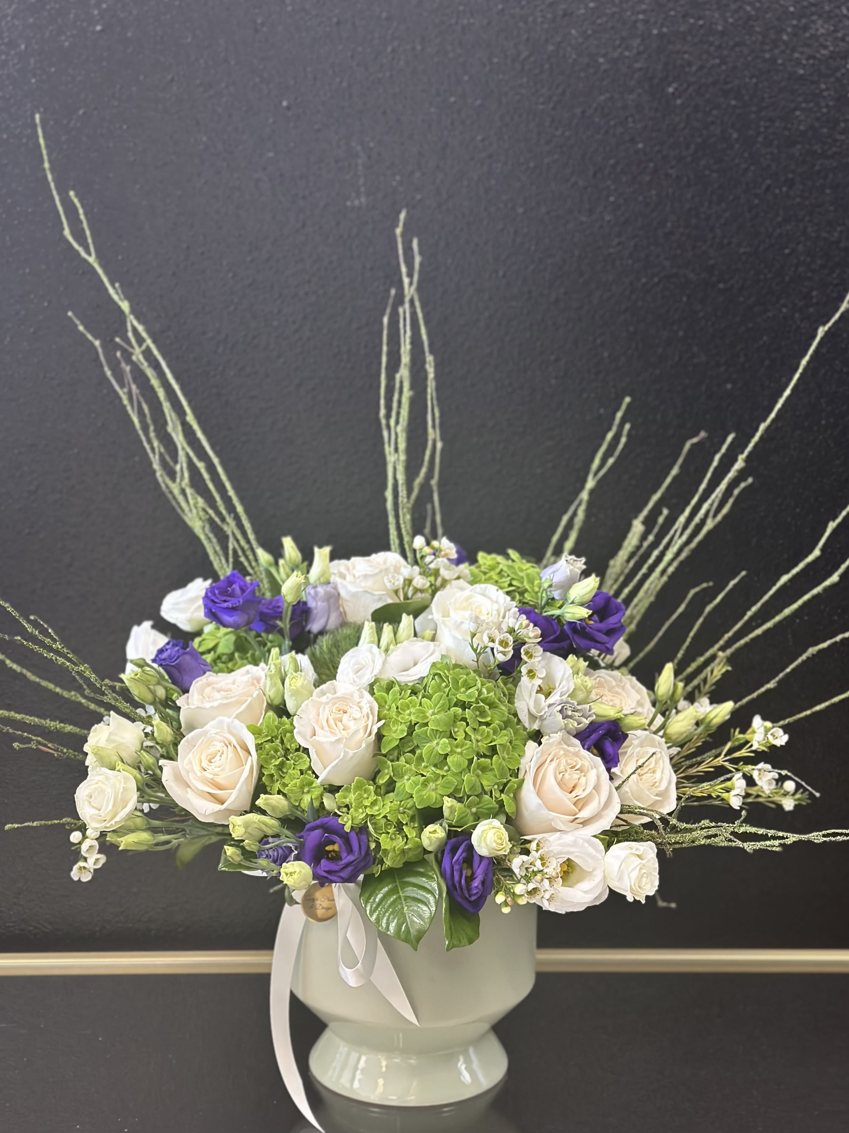 Bouquet of cream and purple roses in a white vase