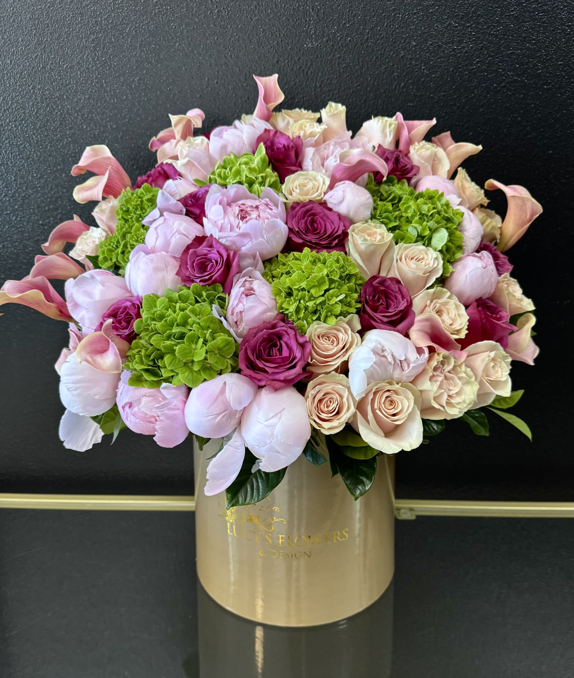Pink and cream bouquet with roses, peonies, calla lilies, and green hydrangeas in a gold box