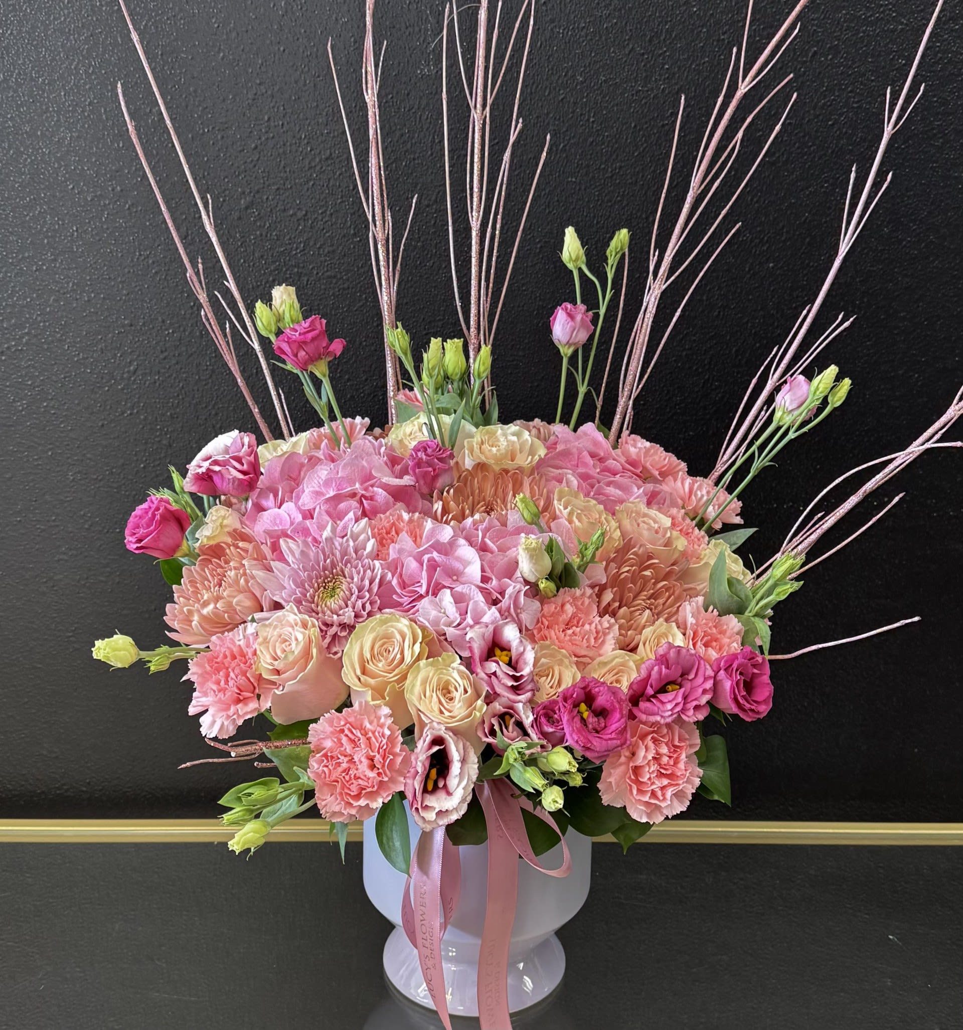 Pink and cream mixed bouquet in a white vase with tall decorative branches