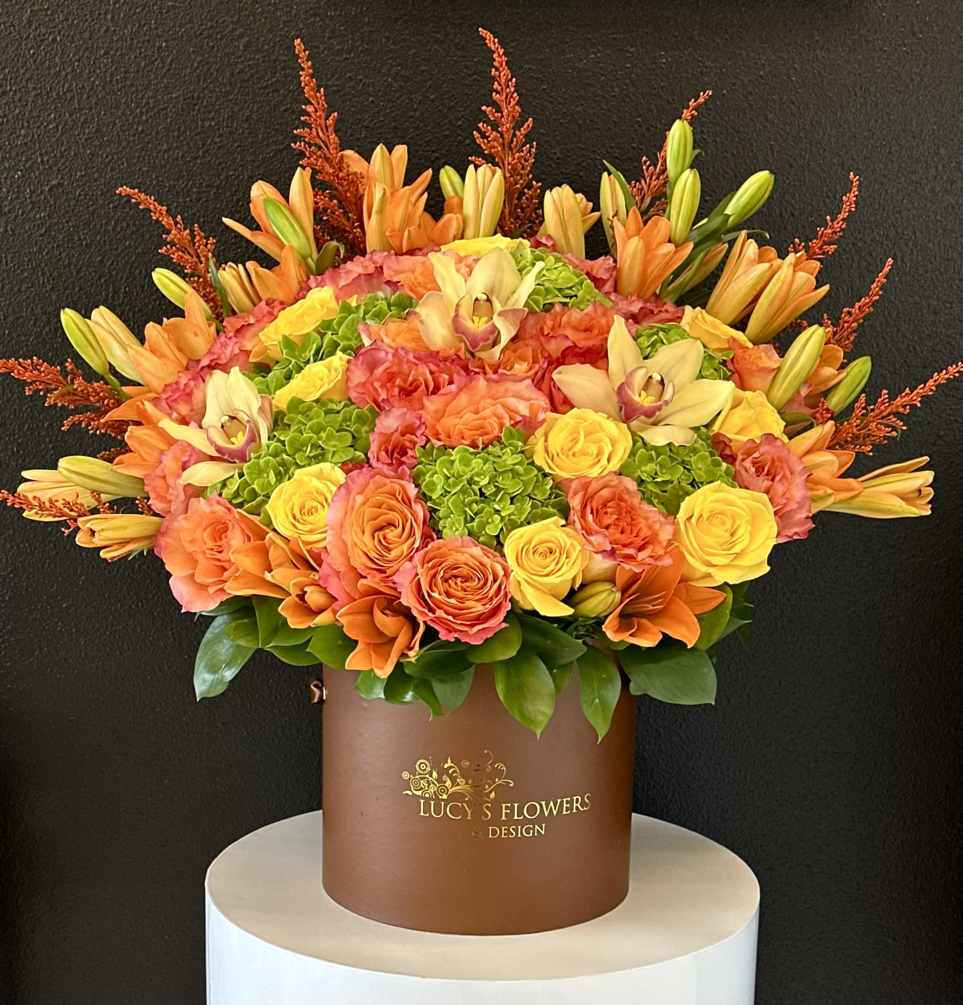 Orange and yellow floral arrangement in a brown hat box