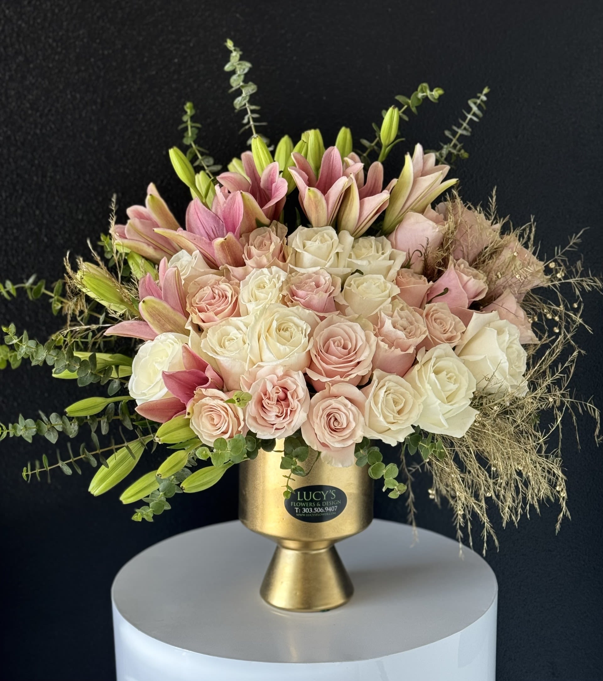 Pink and white roses with lilies in a gold vase