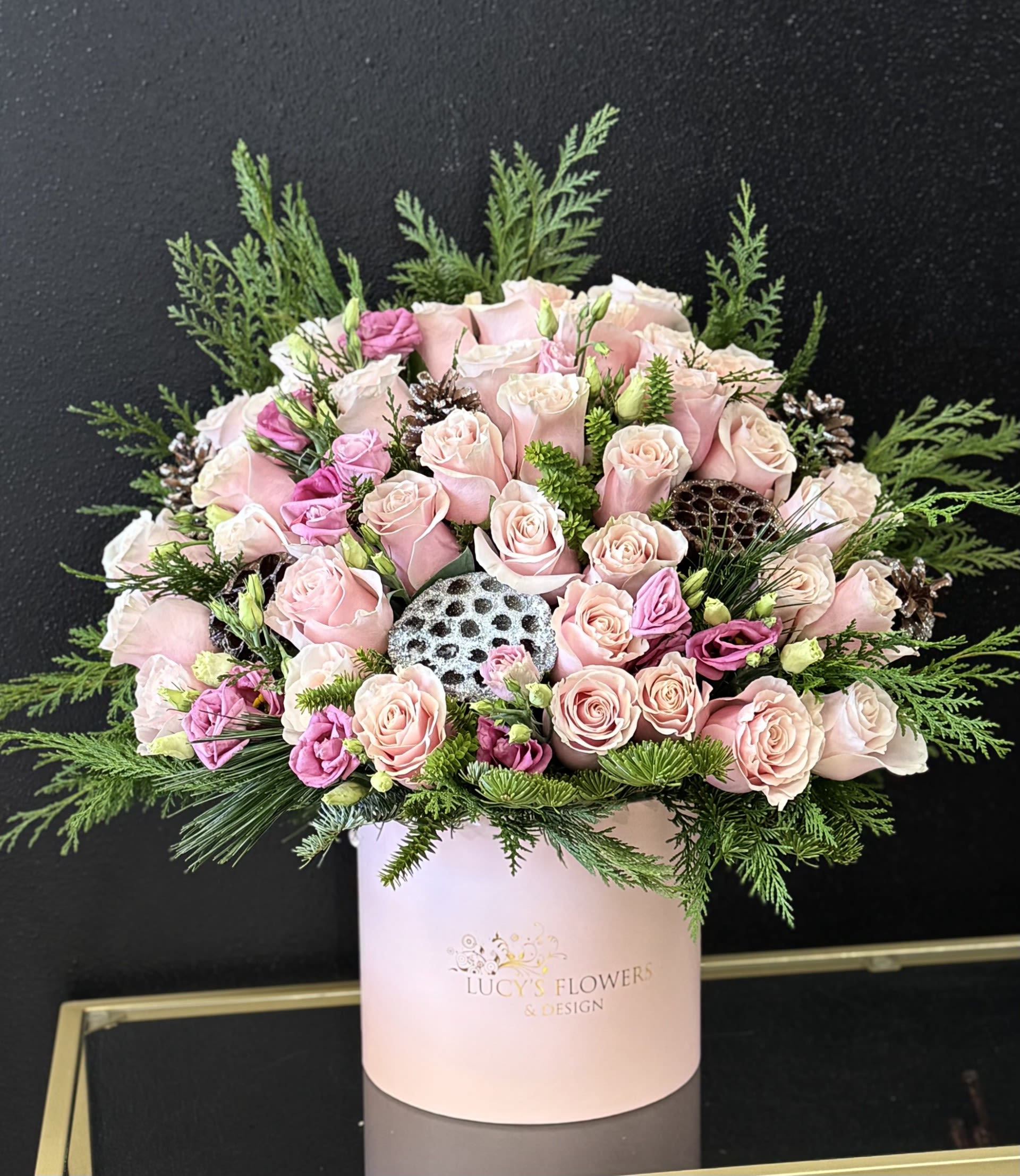 Pink roses and lisianthus in a pale pink hat box with greenery