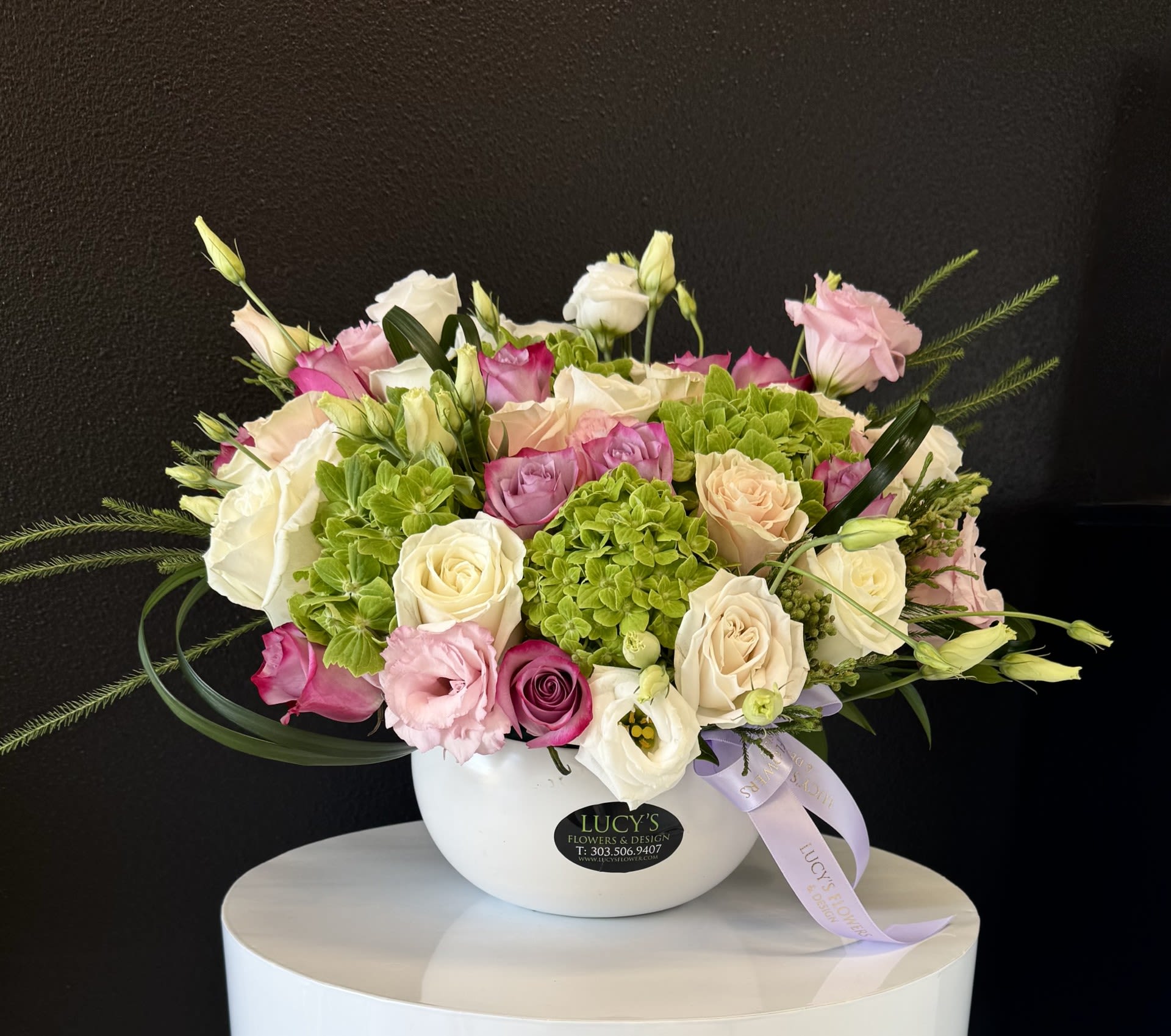 Mixed pink, white, and cream flowers arranged in a white bowl vase
