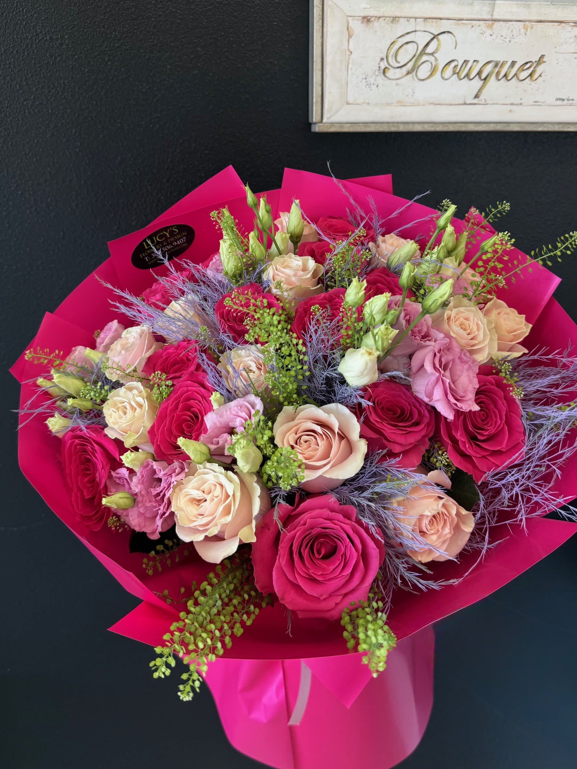 Rosy Charm Hand-Tied Bouquet - A custom-wrapped bouquet featuring two stunning shades of pink roses — soft and bold — hand-tied with premium ribbon and signature wrapping. Elegant, romantic, and designed to impress.   Arrangement Includes: -Fresh Cut Roses &amp; Other Seasonal Flowers -Care Instructions -Custom Wrapping Paper &amp; Ribbon 