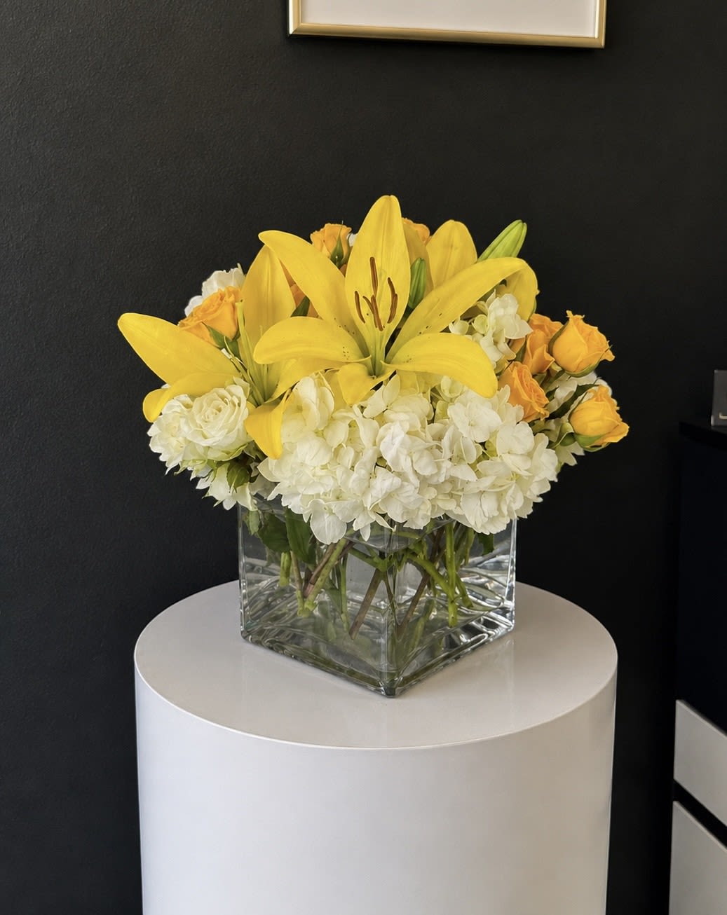 Yellow lilies and white hydrangeas in a clear square vase