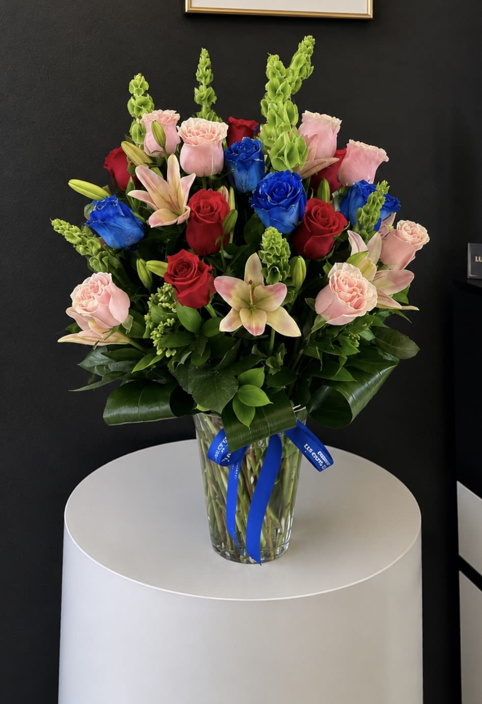 Sugar  - This is the most whimsical way to sweeten somebody's day. This beautiful boho arrangement with peach and hot roses, blue roses, lilies and bells of ireland in a tall vase that will elevate any space. Perfect for Women's Day, Mother's Day, or any birthday.    
