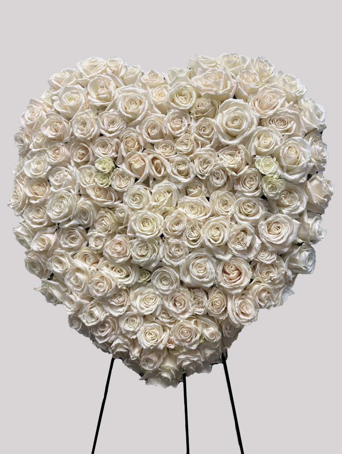 Heart-shaped arrangement of white roses on a stand