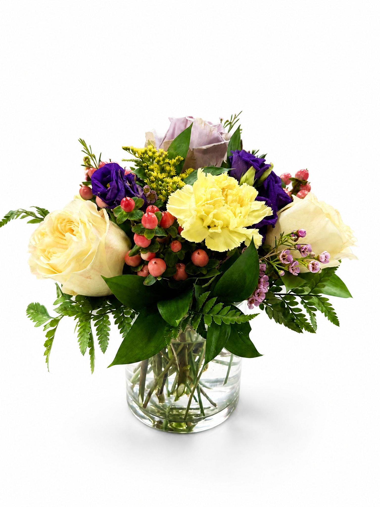 Mixed bouquet of cream, yellow, and purple flowers in a glass vase