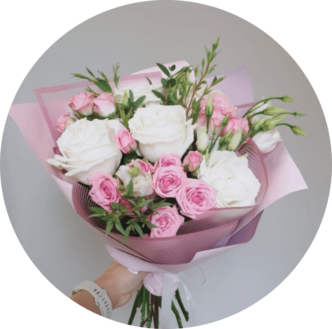 White and Pink Blush - A lush cluster of large white roses paired with soft pink roses and delicate pink lisianthus creates a romantic birthday bouquet or anniversary gift that reads fresh, feminine, and quietly elegant. The mix of fully open blooms and tighter buds gives the recipient a garden-fresh experience - gentle perfume, layered petals, and a soft pastel palette that says "I'm thinking of you" without words.  Hand-tied in a rounded, generous shape, the stems are wrapped in layered pink paper and finished with a crisp white ribbon for a polished presentation ready to give. Sprigs of airy greenery and small spray roses add texture and movement, making this bouquet a beautiful choice for anniversaries, Valentine's Day, birthdays, or a meaningful congratulations - the kind of arrangement that will make her feel truly seen.
