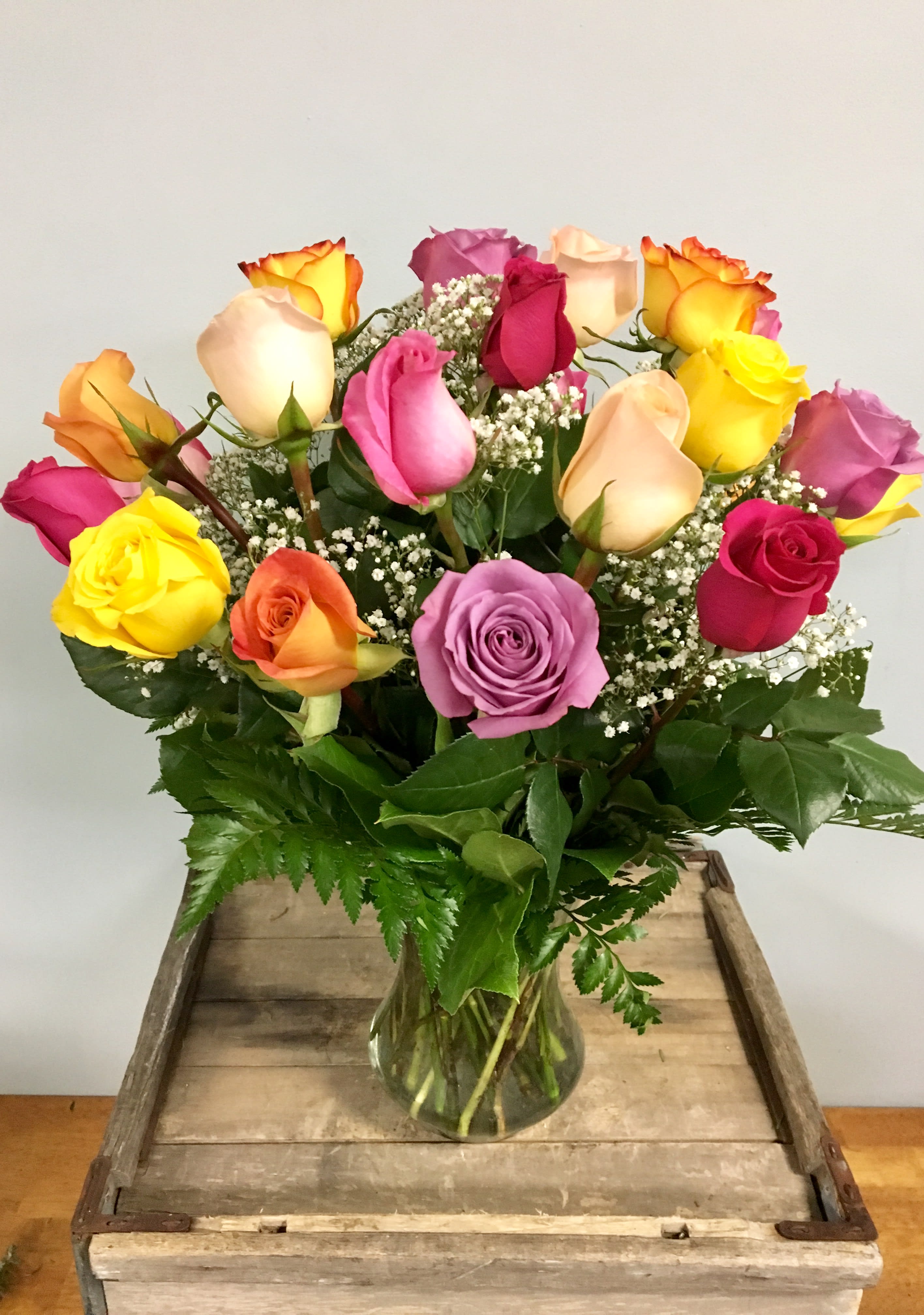 Mixed-color roses in a clear glass vase with baby's breath