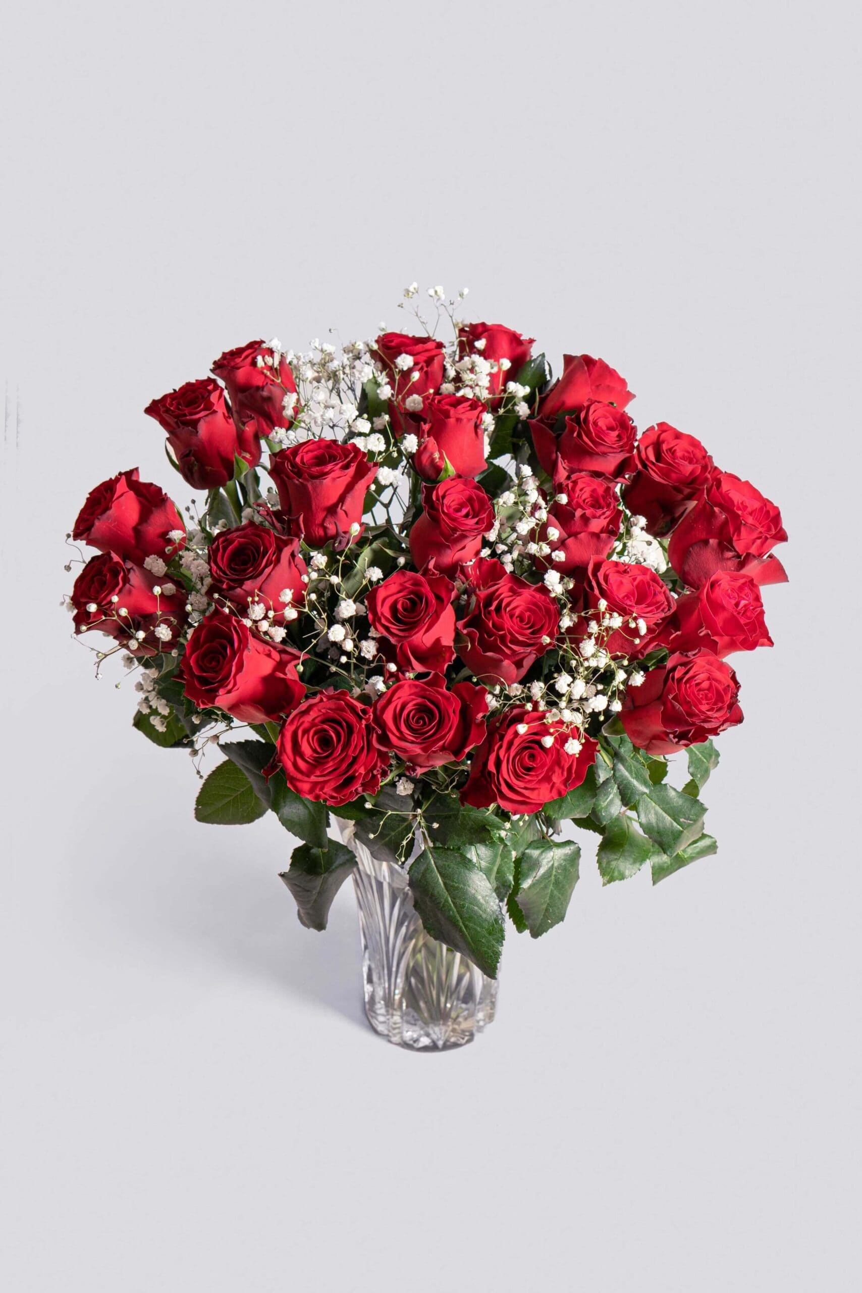 Bouquet of red roses with white baby's breath in a clear glass vase