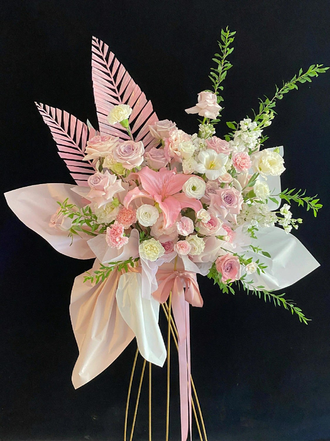 Pink and white floral arrangement with ribbon on tall gold stands