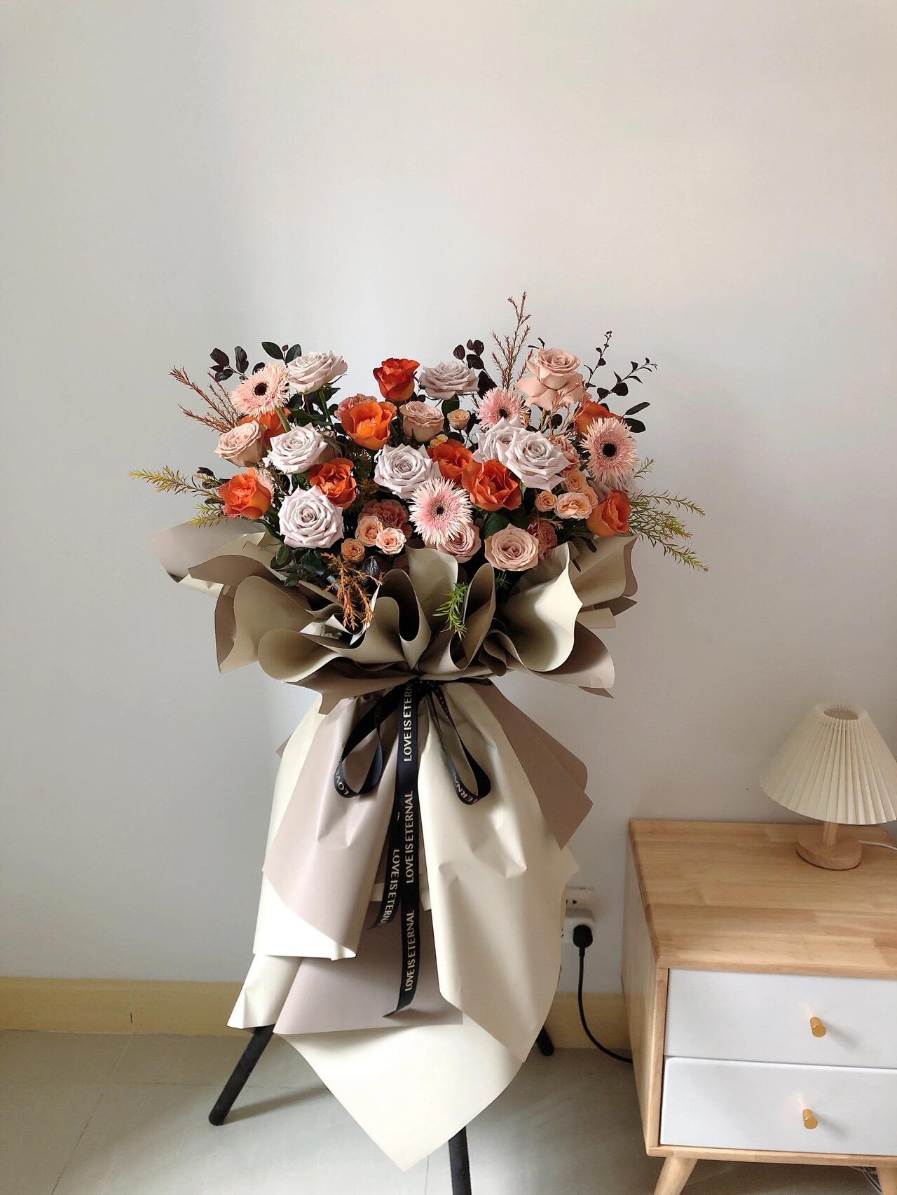 Large bouquet of peach and pink roses with paper wrapping