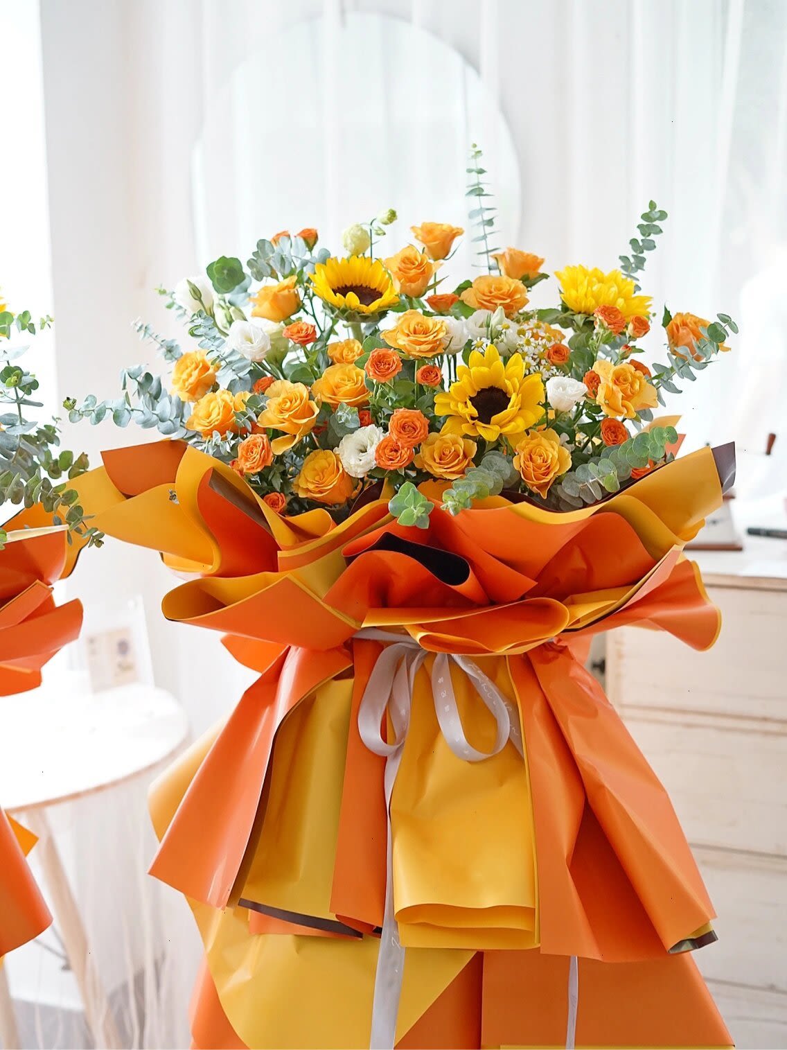 Bouquet of yellow and orange flowers wrapped in bright orange paper