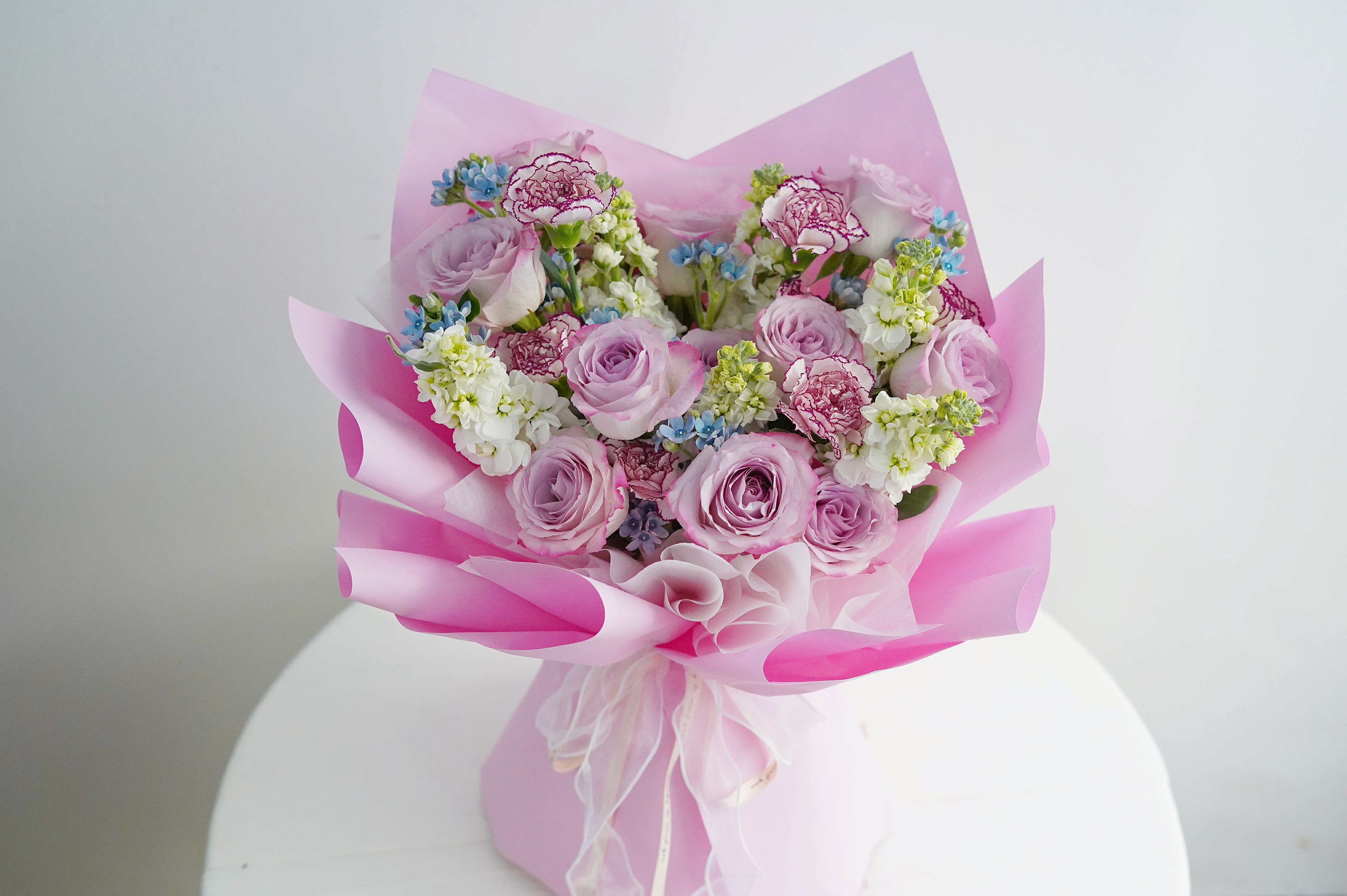 Pink bouquet of roses and carnations wrapped in pink paper