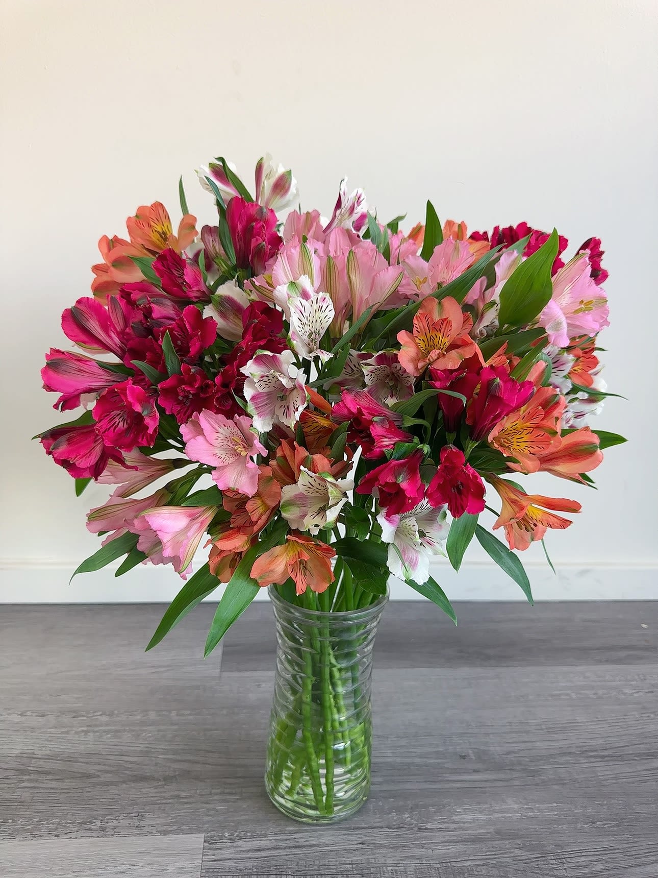Mixed pink and orange flowers arranged in a clear glass vase