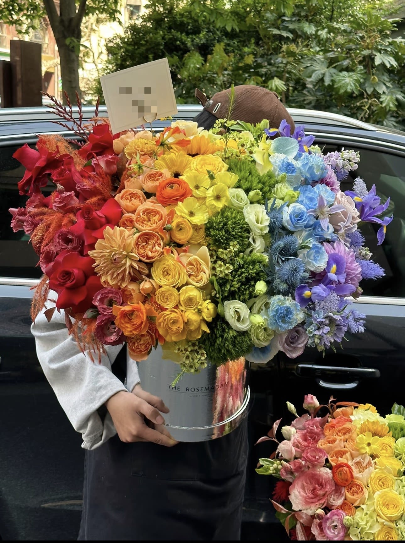 Large rainbow bouquet in a silver bucket held by a person
