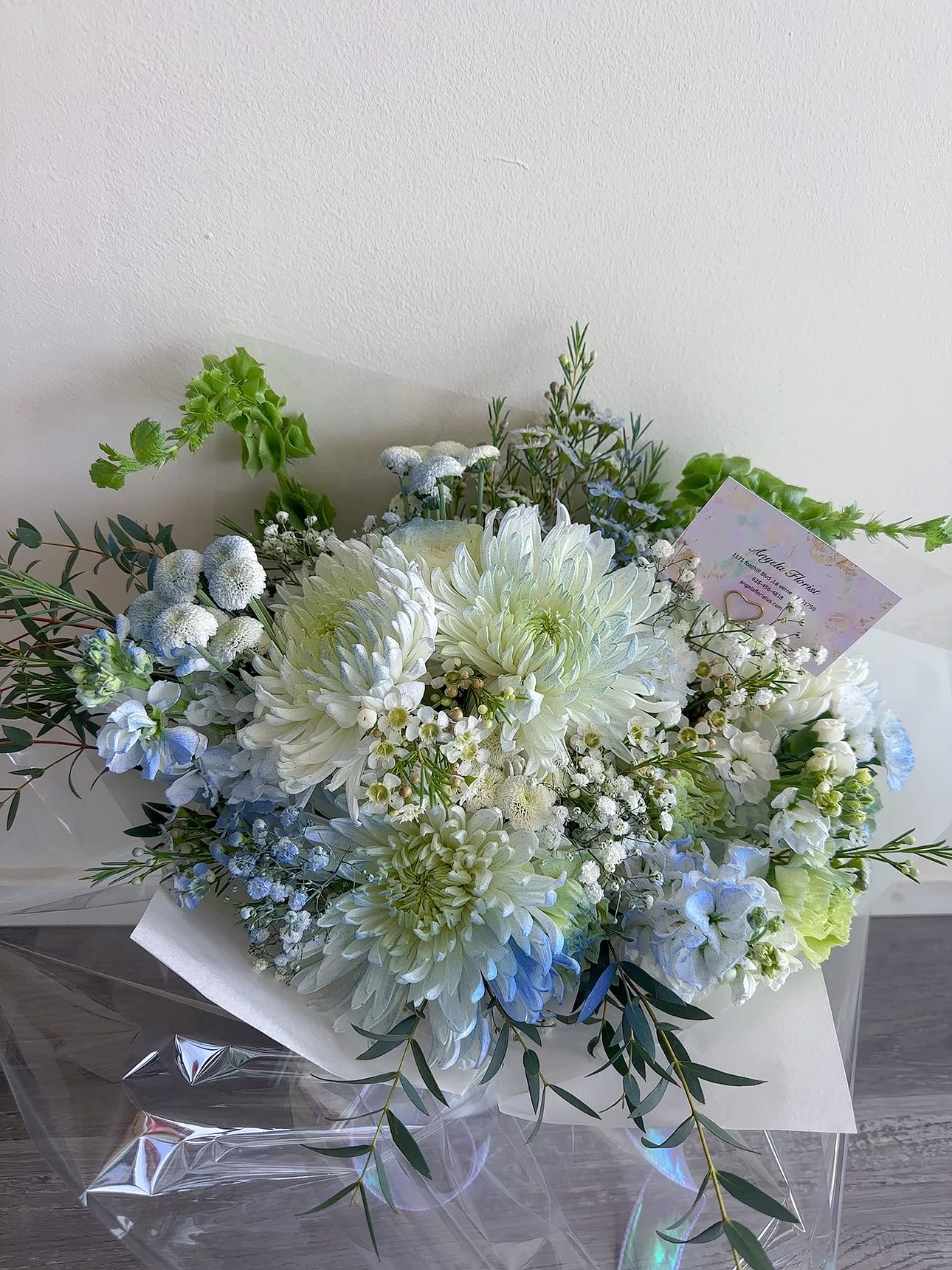 Bouquet of white and pale blue flowers wrapped in white paper